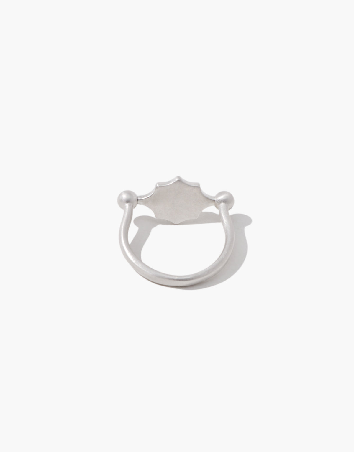 Las Swivel Ring | Scallop Metal shown in a matte sterling silver finish, the scalloped face resting between two beaded posts. Las Swivel Ring | Scallop Metal by CLED.