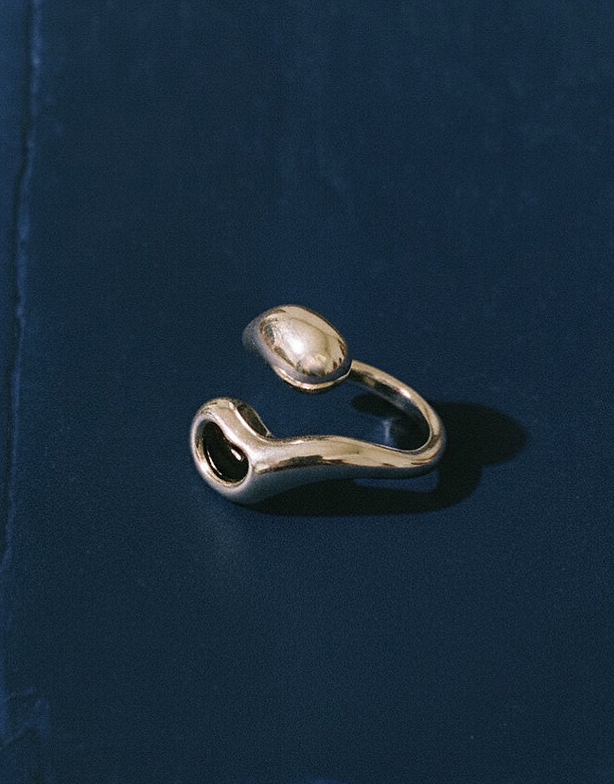 silver ring with black stone setting in dark blue background