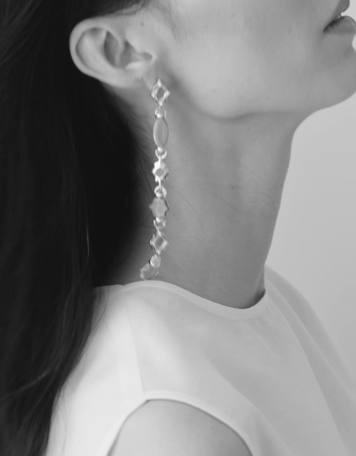 Cadence Linear Earring in clear glass in black and white, a long drop of Eco Gems moving along the neck. Cadence Linear Earring by CLED.
