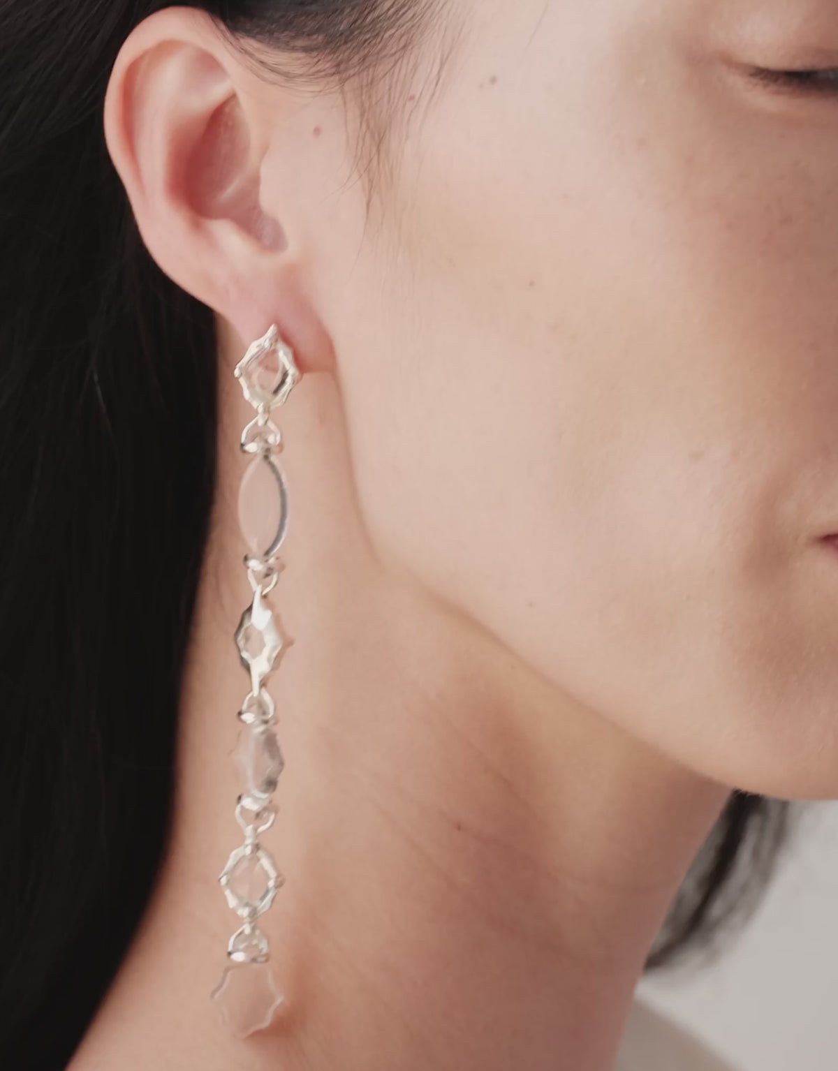 Cadence Linear Earring in clear glass turning with the head, graduating Eco Gems catching the light. Cadence Linear Earring by CLED.