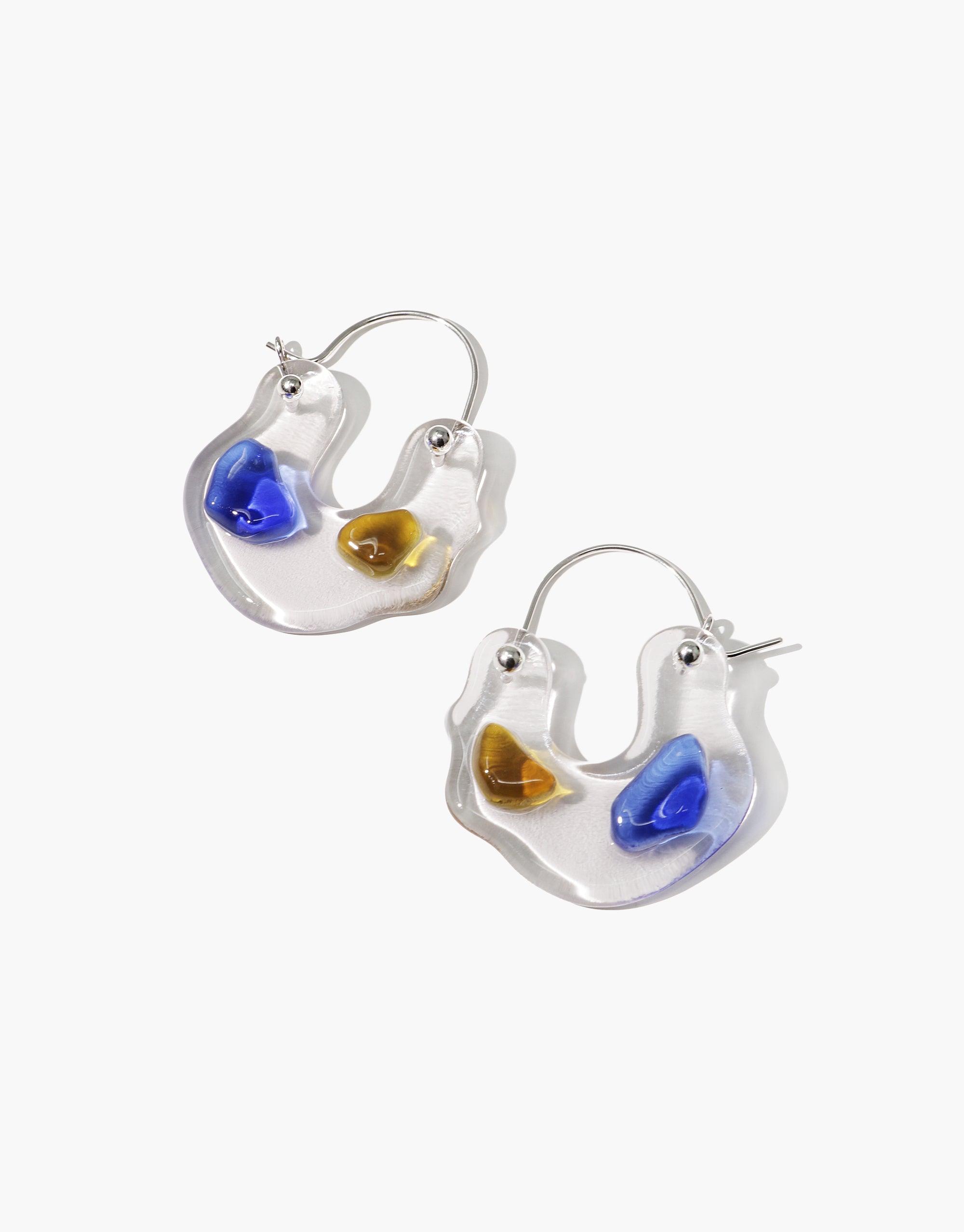 Handcrafted Ray Hoop Earrings featuring transparent curved shapes with blue and amber eco gems, representing prism-like spectral colors. Sterling silver hoops showcase sustainable design and artisanal craftsmanship. Unique, eco-friendly jewelry by CLED.