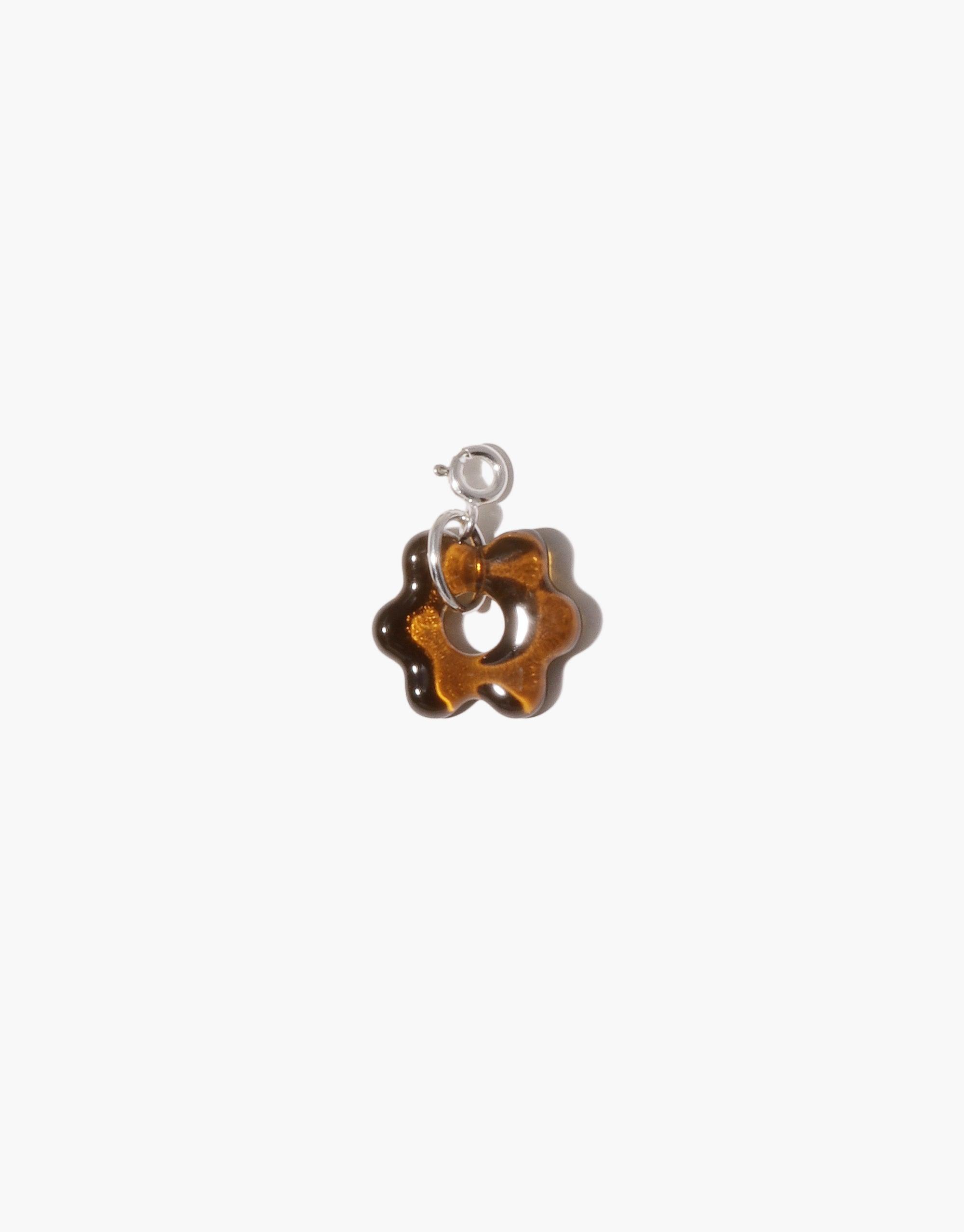Avens Icon Charm featuring a small amber-colored glass flower pendant with a silver loop attachment. Handcrafted from upcycled eco-friendly materials. Versatile accessory for necklaces or bracelets. Avens Icon Charm by CLED.