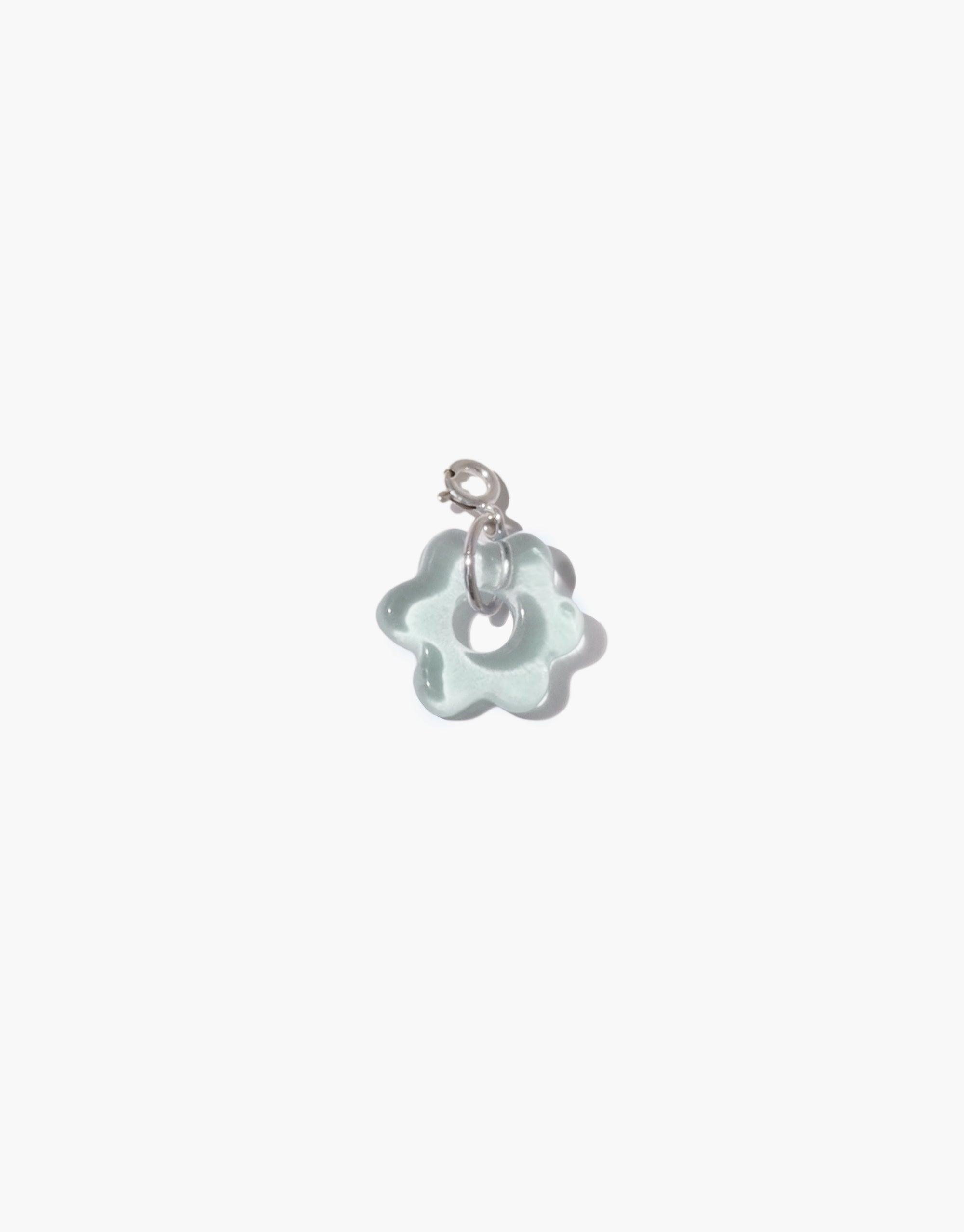 Delicate flower-shaped charm in pale blue upcycled glass with silver attachment loop, part of the Avens Icon Charm collection. Handcrafted eco-friendly jewelry piece for necklaces or bracelets. Sustainable and unique accessory by CLED. Avens | Icon Charm.