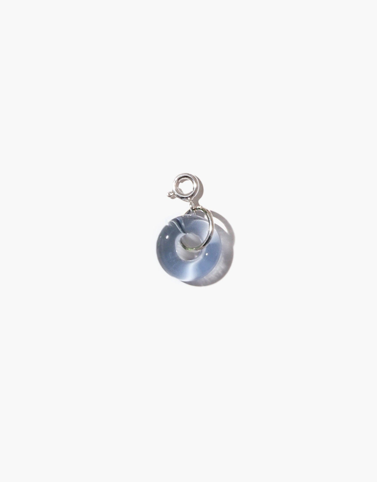 Donut Icon Charm featuring a translucent glass ring pendant in light blue color, attached to a silver loop. Handcrafted eco-friendly jewelry piece made from upcycled glass. Perfect for necklaces or bracelets. Unique and sustainable accessory by CLED.