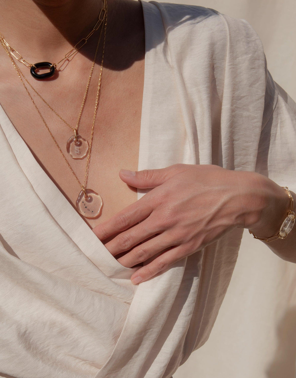 Elegant layered necklaces featuring personalized eco gem pendants with clear engraving, showcasing the Messenger Necklace collection. Delicate gold chains complement a white outfit, embodying sustainable luxury and meaningful communication. CLED Messenger Necklace | Clear Engraving