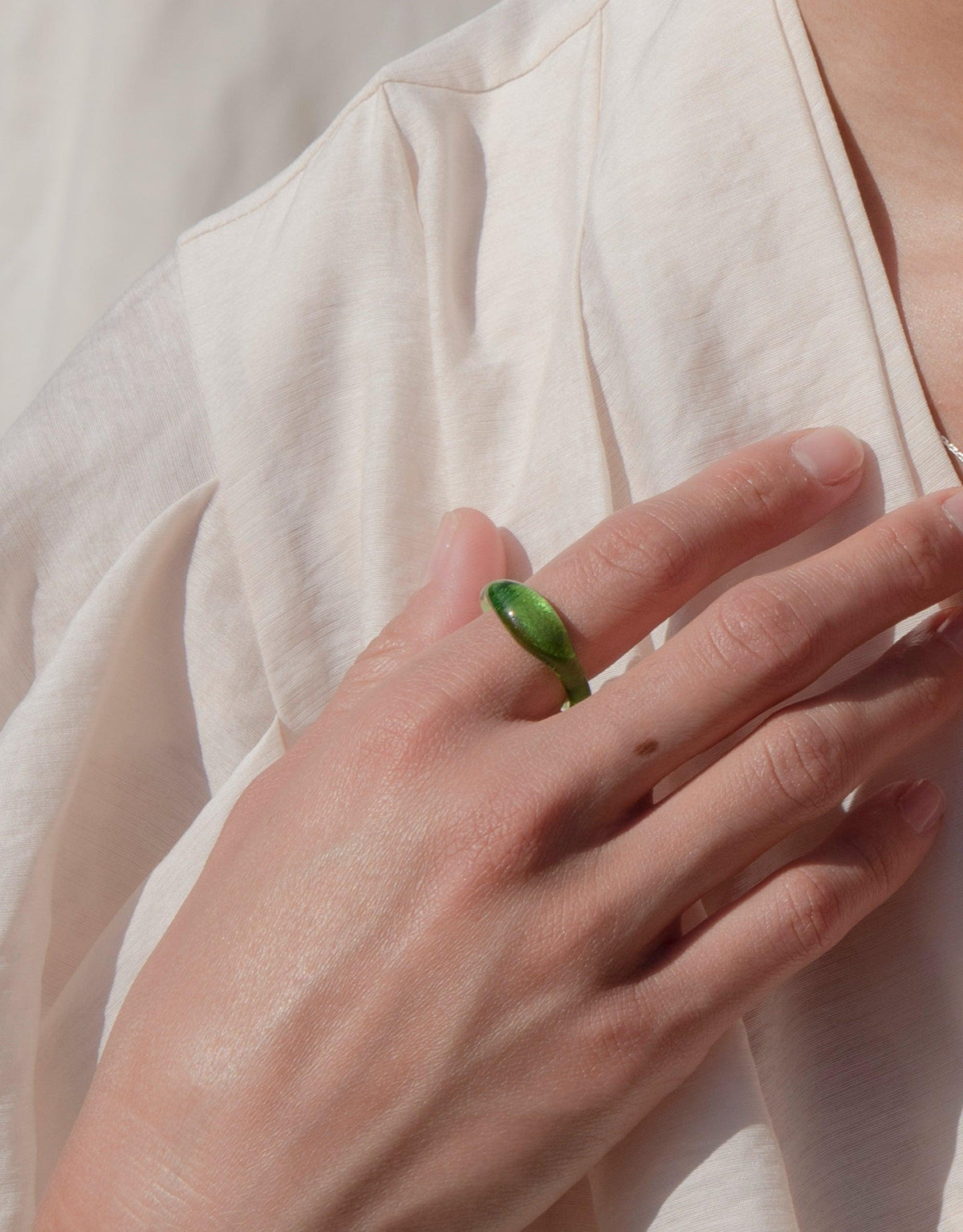 Close-up of hand wearing a green eco-friendly signet ring from the Messenger Collection, showcasing the Signet Ring Original by CLED. The ring features a vibrant, handcrafted eco gem made from repurposed glass, demonstrating sustainable jewelry design.