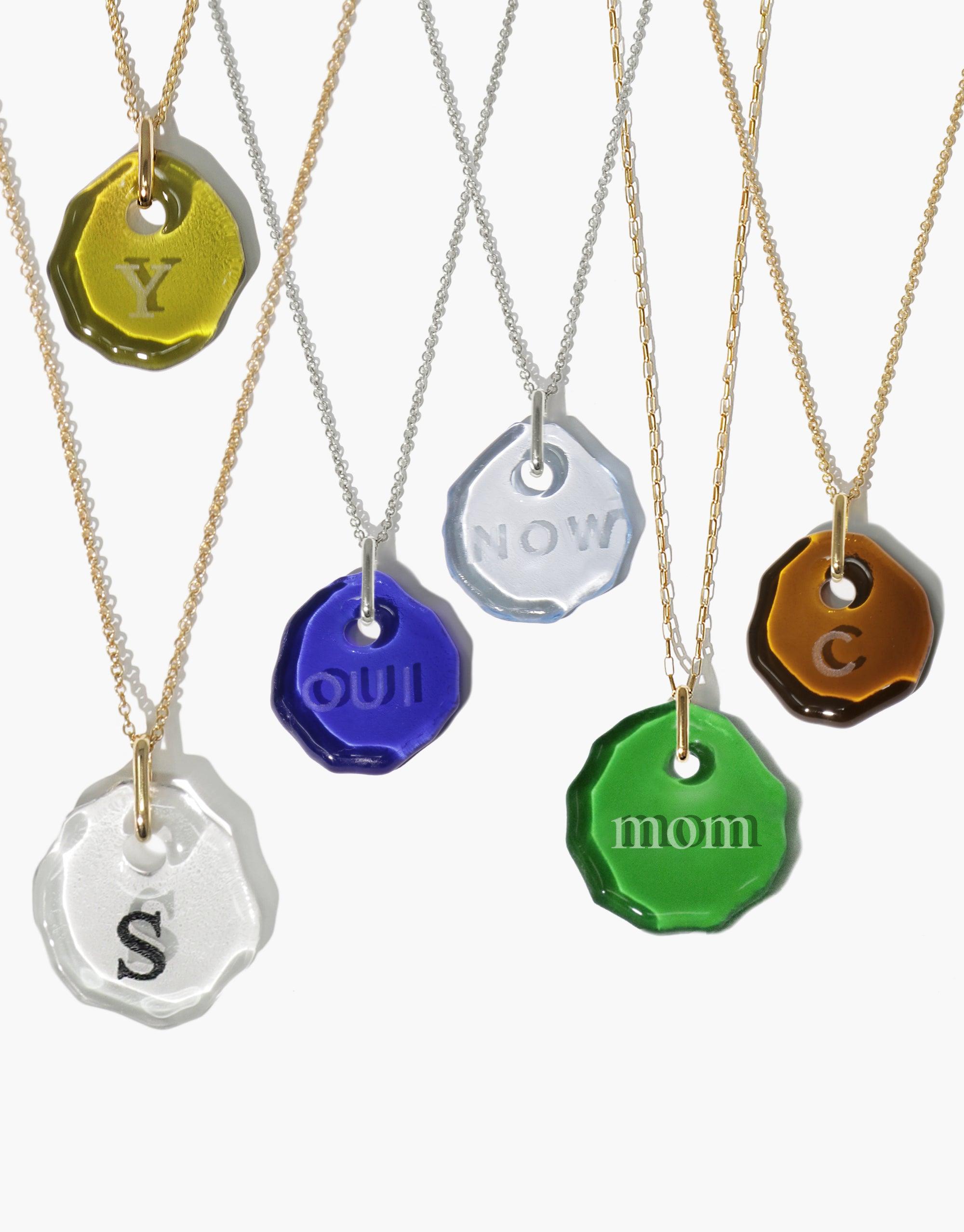 Colorful eco-friendly glass pendants with engraved messages on delicate chains, showcasing the Messenger Necklace collection. Each pendant features a unique shape and color, offering personalized jewelry options for sustainable fashion. Messenger Necklace | Clear Engraving by CLED