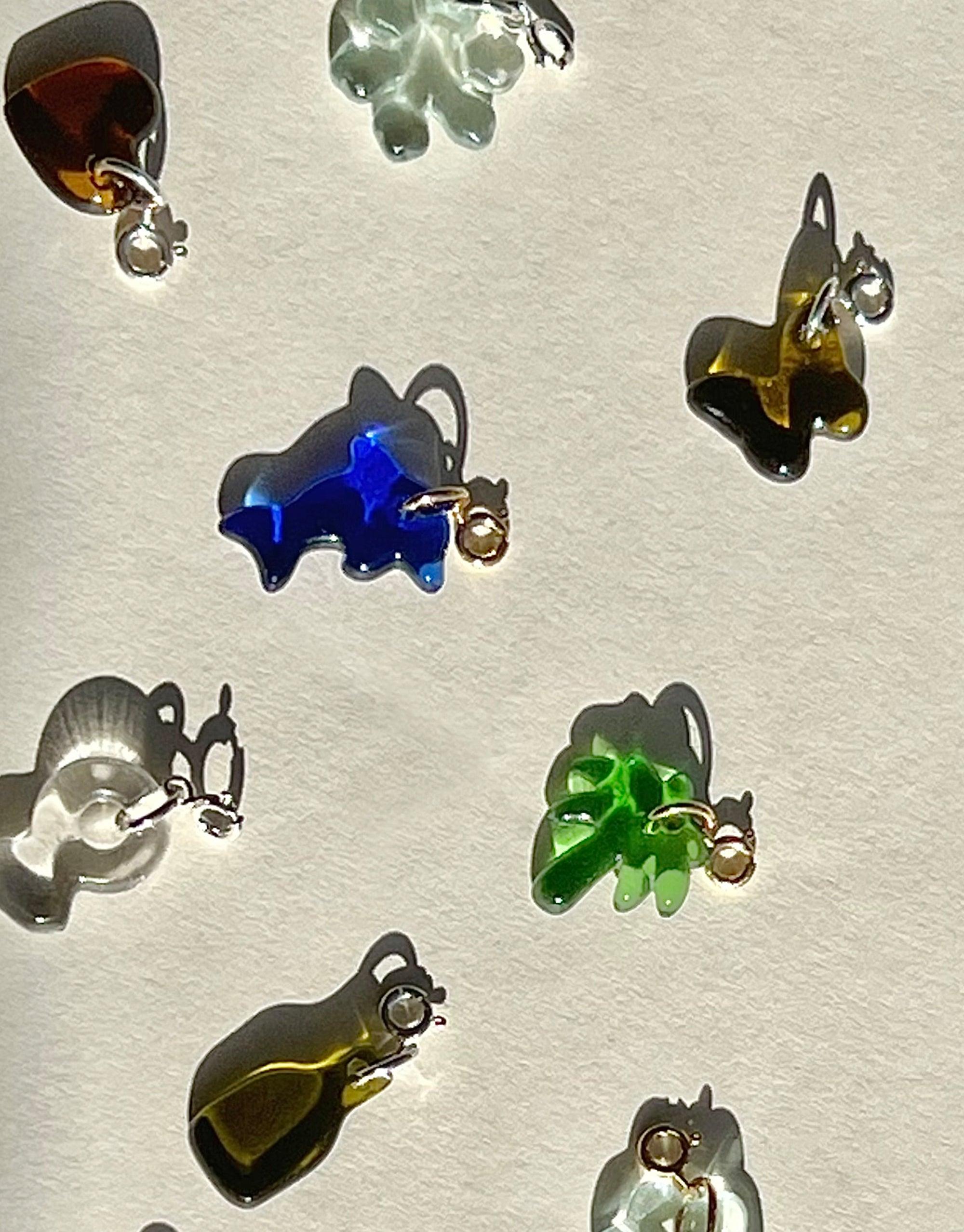 Assortment of colorful glass Icon Charms in various shapes including dolphin, butterfly, and abstract forms, showcasing upcycled eco gems repurposed from discarded bottles. Handcrafted sterling silver or gold vermeil attachments for versatile jewelry customization. Dolphin | Icon Charm by CLED