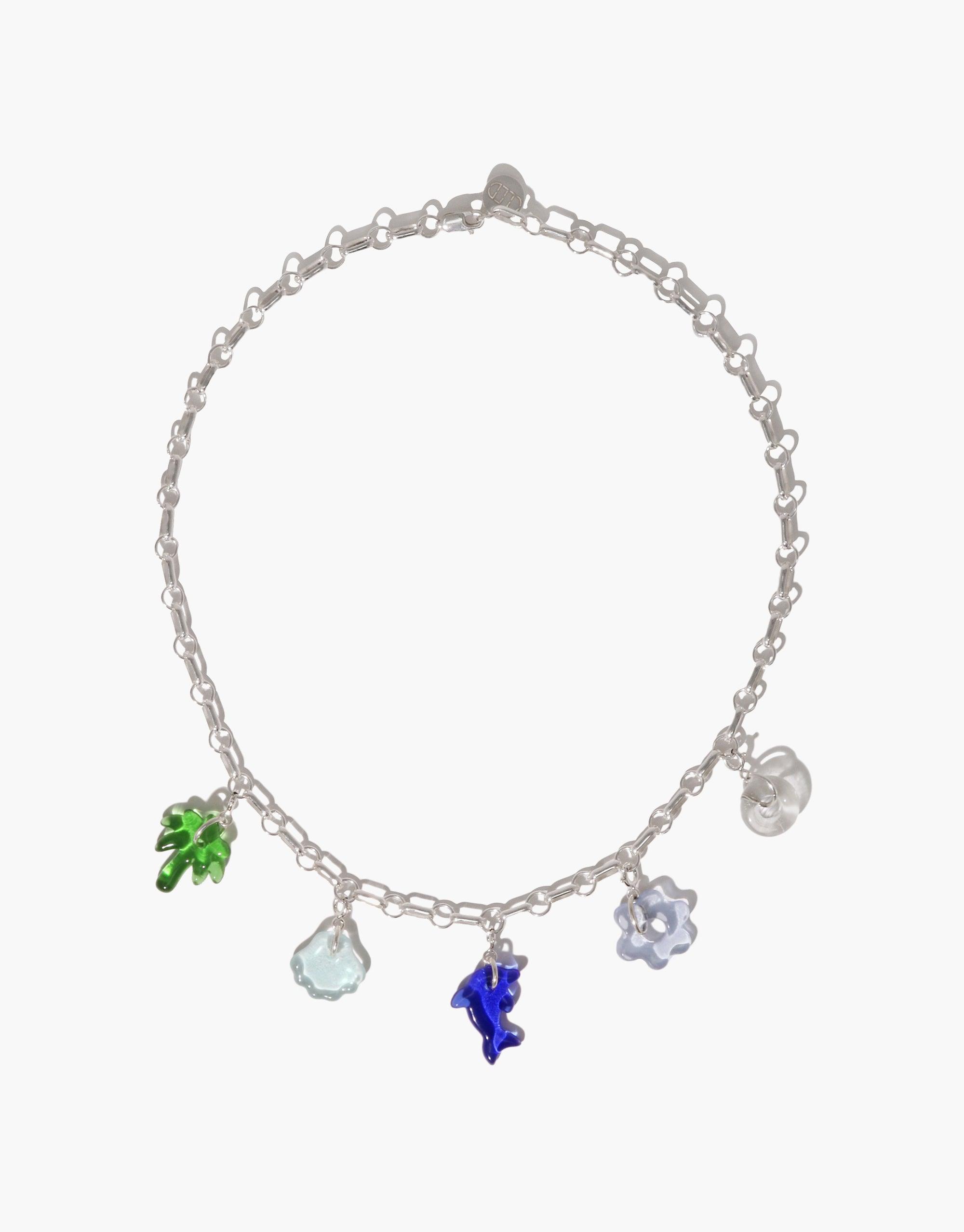Delicate silver chain necklace with colorful glass charms including green leaf, blue dolphin, and flower shapes. Versatile Icon Chain Necklace | A for customizable styling. Mix and match charms or wear alone for a sleek look. Elegant and eco-friendly accessory by CLED.