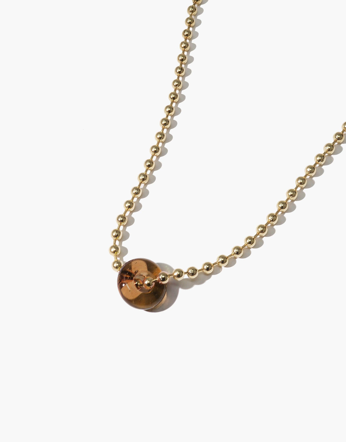 Elegant gold chain necklace featuring a single amber-colored eco gem bead, showcasing the Donut Ball Necklace design. Handcrafted with sustainable materials, this piece embodies CLED's commitment to eco-friendly jewelry and prism-inspired aesthetics.