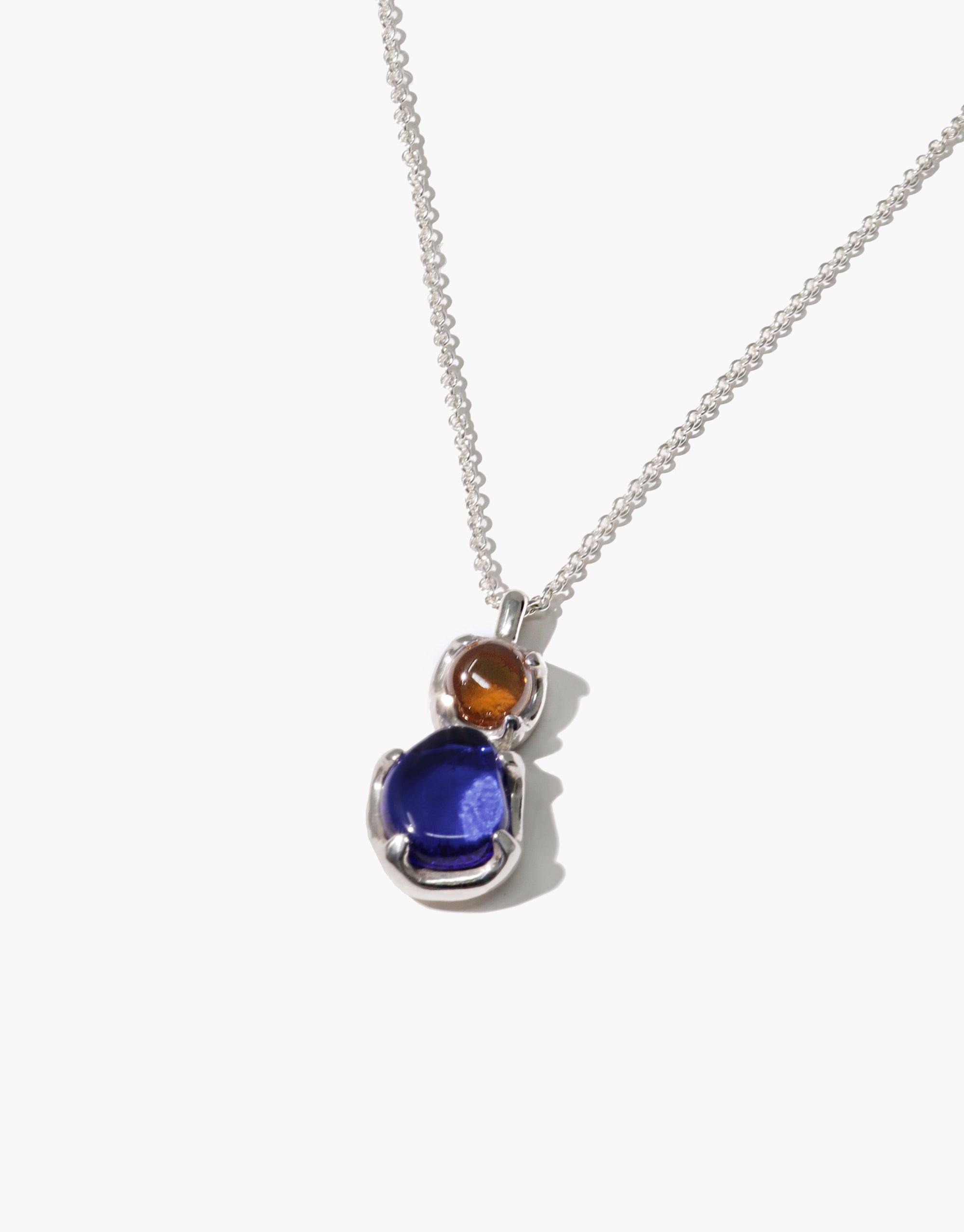 Elegant Duo Beam Necklace featuring a pendant with blue and amber eco gems on a delicate silver chain, showcasing sustainable luxury and prismatic colors. Handcrafted jewelry inspired by light refraction, perfect for eco-conscious fashion enthusiasts. CLED Duo Beam Necklace.