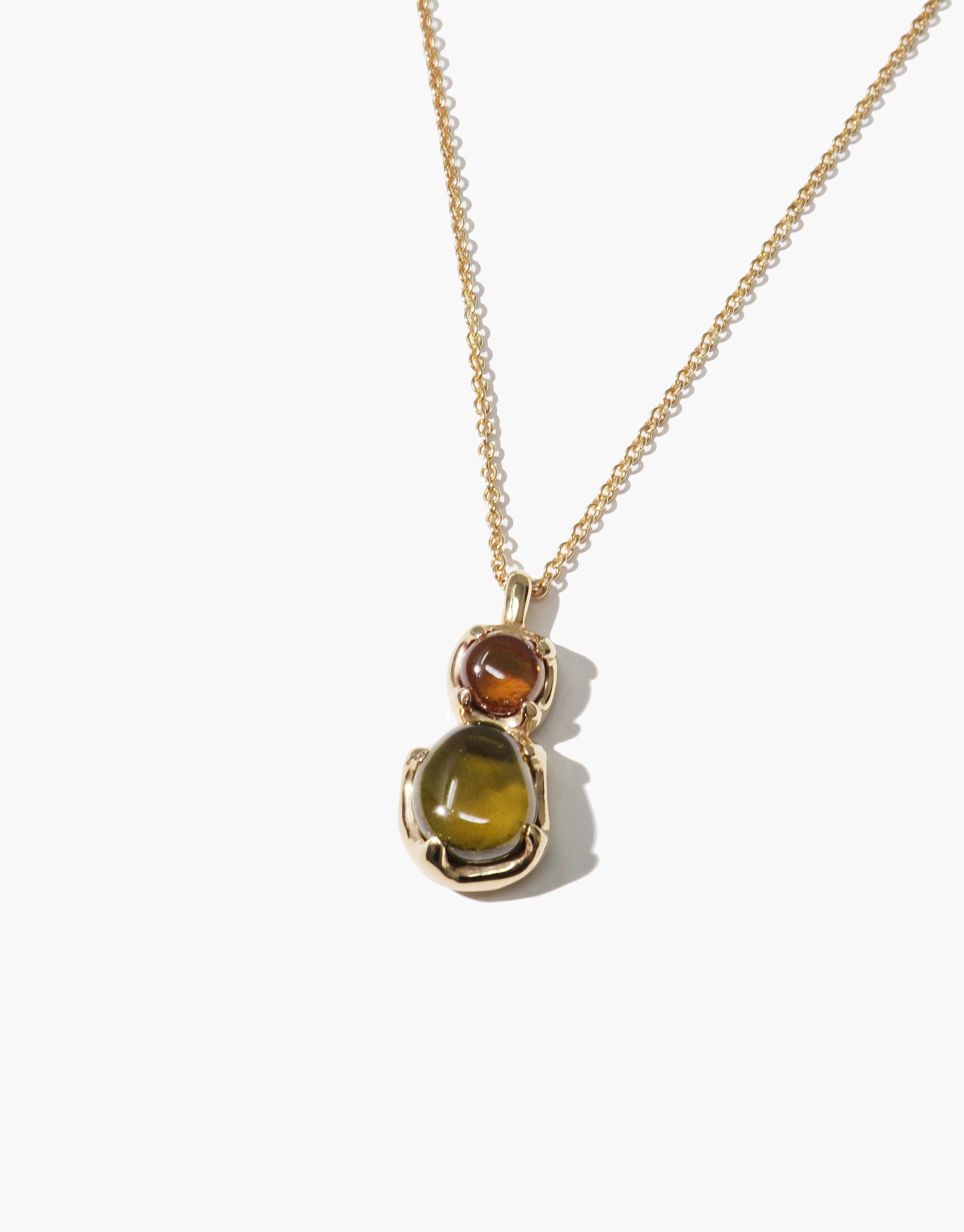 Elegant Duo Beam Necklace featuring two eco gems in amber and olive tones, set in a golden pendant on a delicate chain. Handcrafted with upcycled glass, showcasing sustainable luxury and prismatic beauty. CLED Duo Beam Necklace.