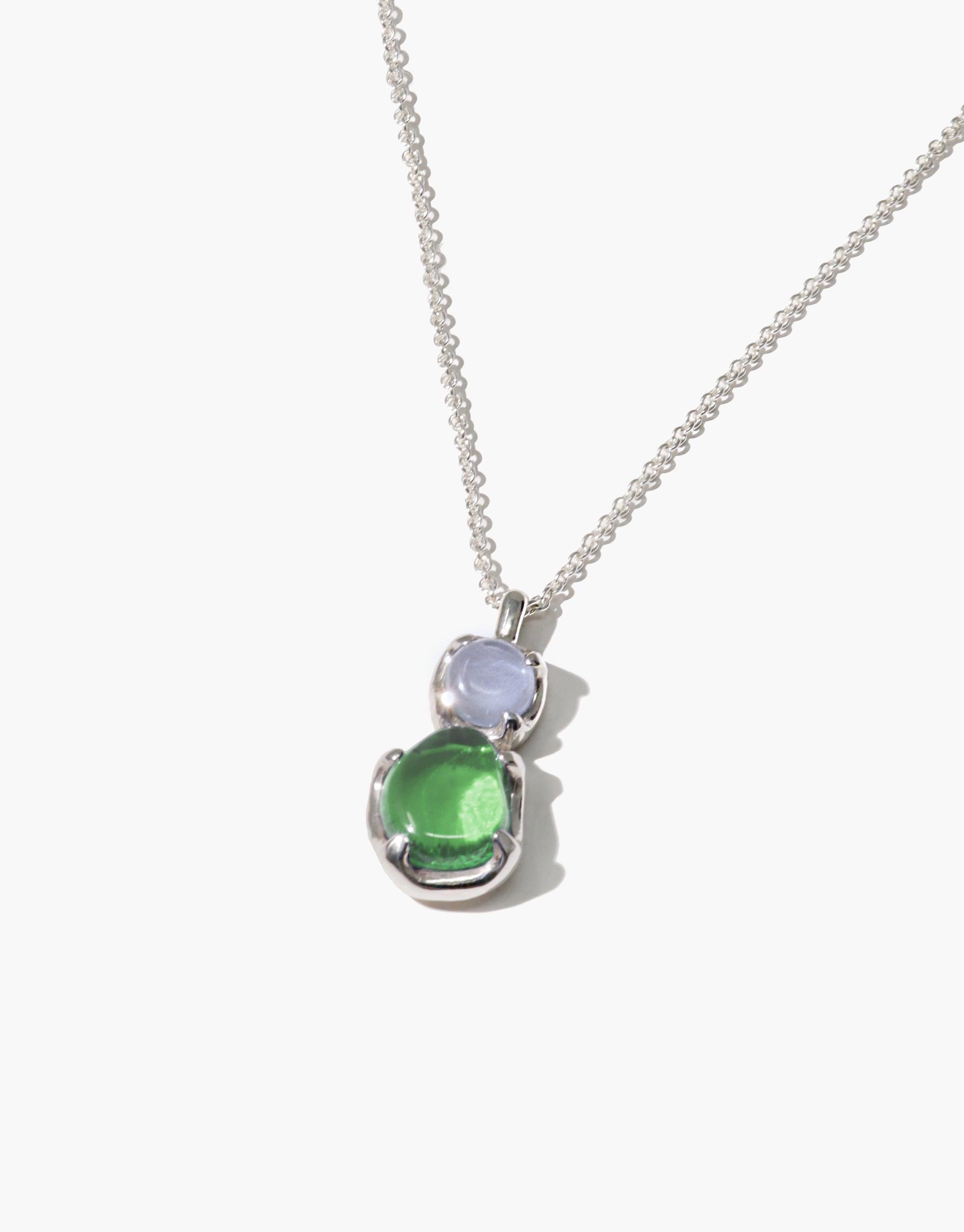 Duo Beam Necklace featuring two circular eco gems in light blue and green, suspended on a delicate silver chain. Handcrafted pendant showcasing sustainable materials and prismatic colors. Elegant accessory representing rays of light. CLED Duo Beam Necklace.
