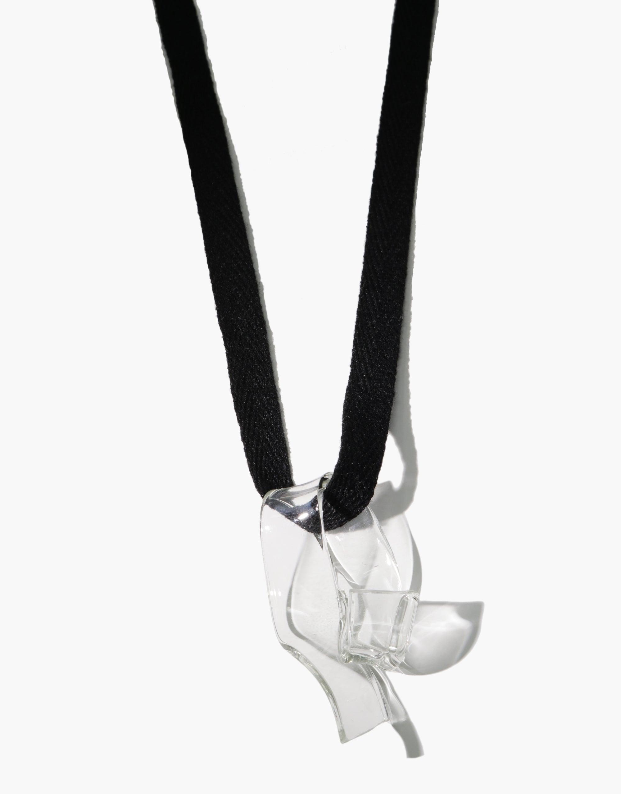 Ribbon Necklace featuring a hand-formed serpentine glass pendant on a black cotton ribbon. The eco-friendly pendant, made from repurposed glass, showcases a unique curved shape. Sustainably crafted and customizable accessory. CLED