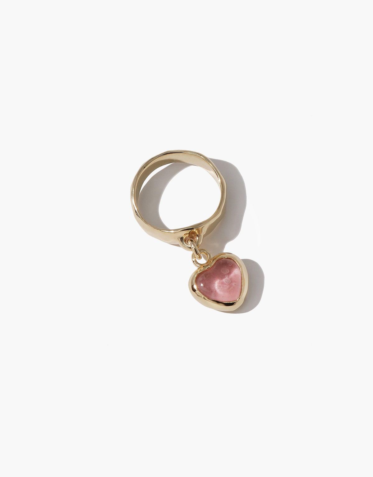 Gold-toned ring with a dangling pink heart-shaped charm, showcasing the Heart Dangling Ring. Handcrafted design featuring upcycled eco gem, perfect for sustainable jewelry enthusiasts. CLED