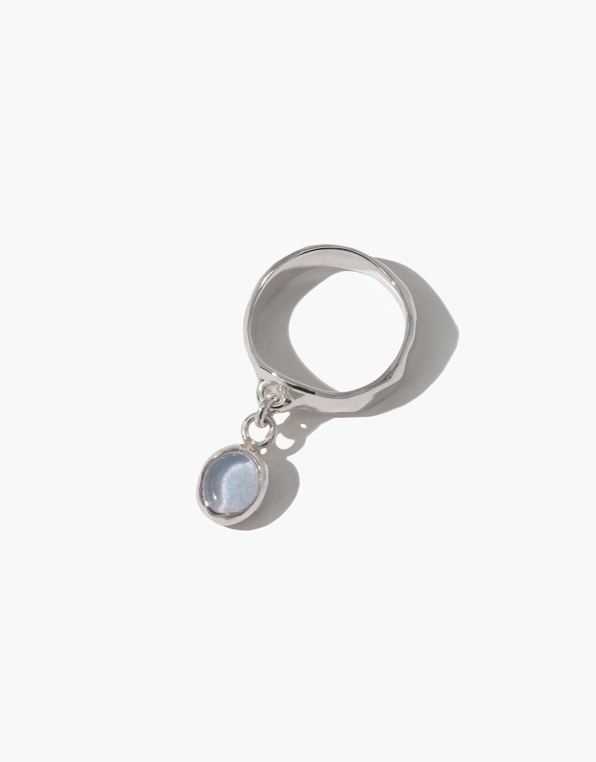 Oval Dangling Ring featuring a silver band with a delicate charm pendant. The charm appears to be a small, round pale blue stone set in a silver bezel. Elegant and minimalist design, perfect for everyday wear. Handcrafted eco-friendly jewelry by CLED.