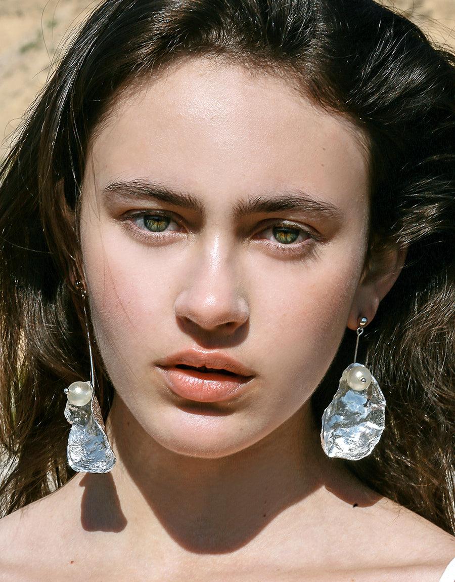 Sustainable eco-friendly dangle earrings with orb posts and recycled glass pearls. Iridescent metal shell texture catches light. Handcrafted in Los Angeles. Not A Pearl Earring by CLED.
