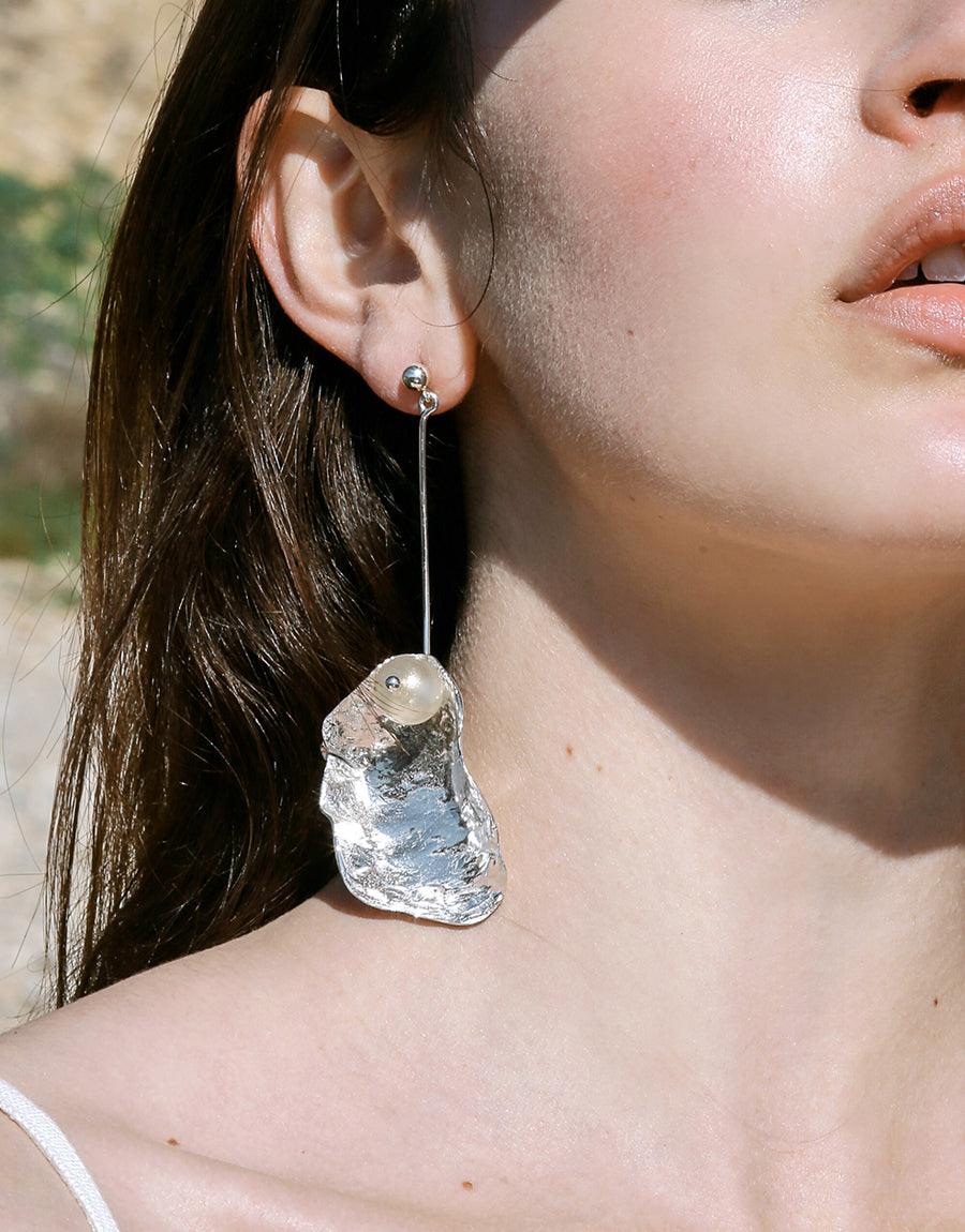 Sustainable "Not A Pearl Earring" featuring a recycled glass Eco Gem dangle on a sterling silver orb post. The textured metal shell gleams in the light, showcasing its unique beauty. Handcrafted, eco-friendly alternative to traditional pearls. CLED