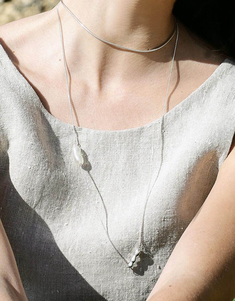 Elegant Shoreline Long Necklace featuring delicate sterling silver chain with sustainable pearl Eco Gem and water drop pendant, perfect for layering or wearing solo. Handcrafted in Los Angeles using repurposed glass, showcasing minimalist design and eco-conscious craftsmanship. CLED Shoreline Long Necklace.