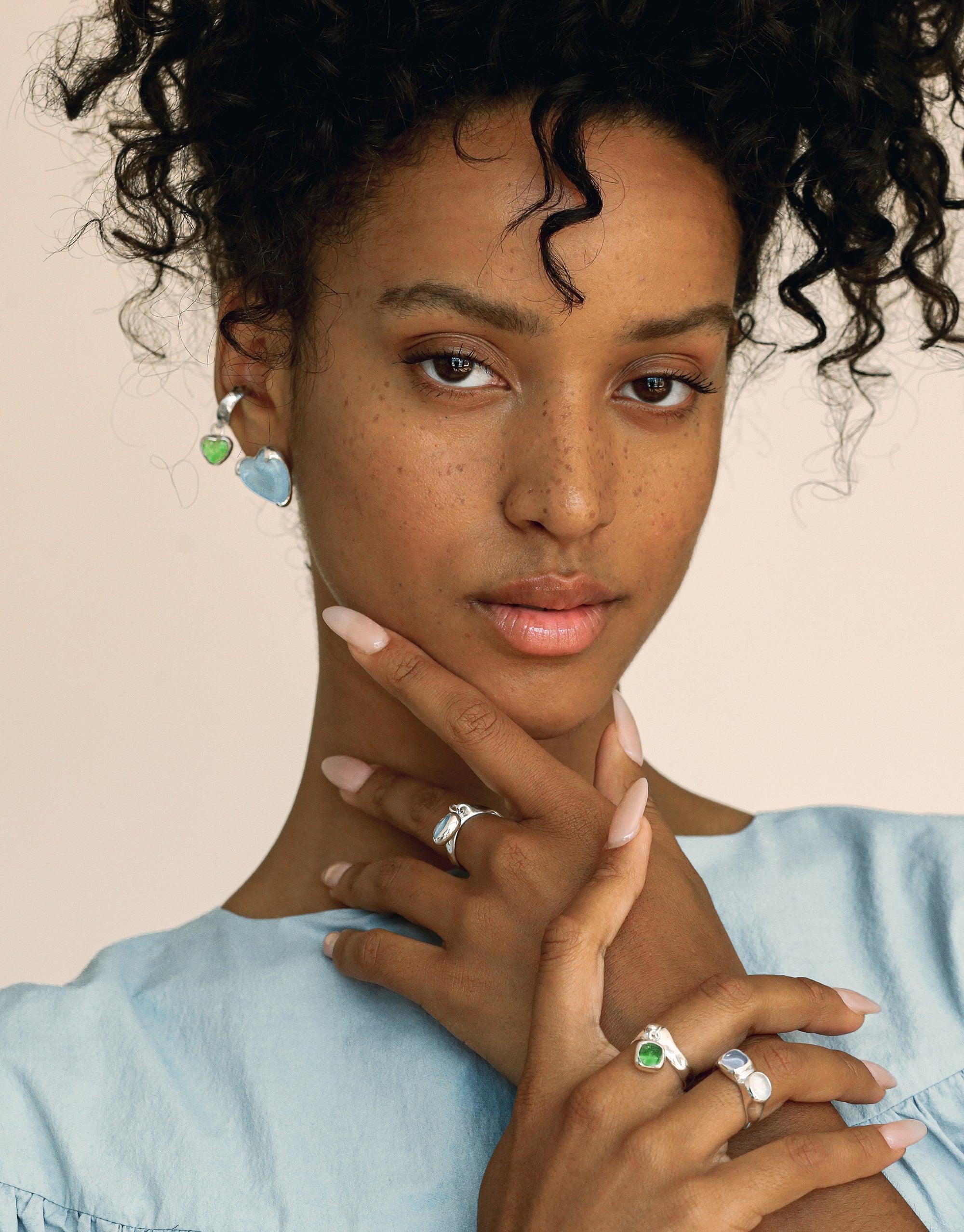 Square Dangling Ring featured on a woman with curly hair, showcasing a silver ring with a blue stone, reflecting CLED's eco-conscious design using repurposed glass into elegant jewelry.