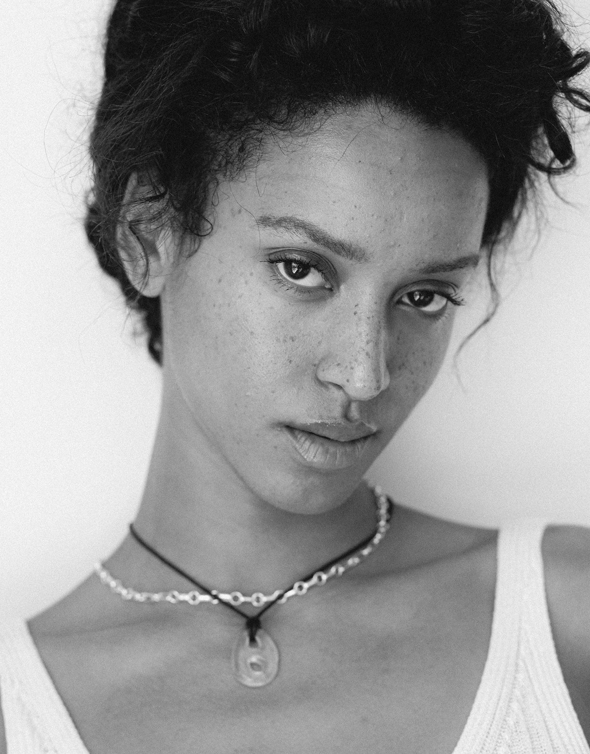 Black and white close-up portrait showcasing the Sculptural Small Charm Necklace | B. Delicate choker-style necklace with handcrafted charm made from upcycled glass, highlighting sustainable jewelry design. Elegant and eco-friendly accessory by CLED.