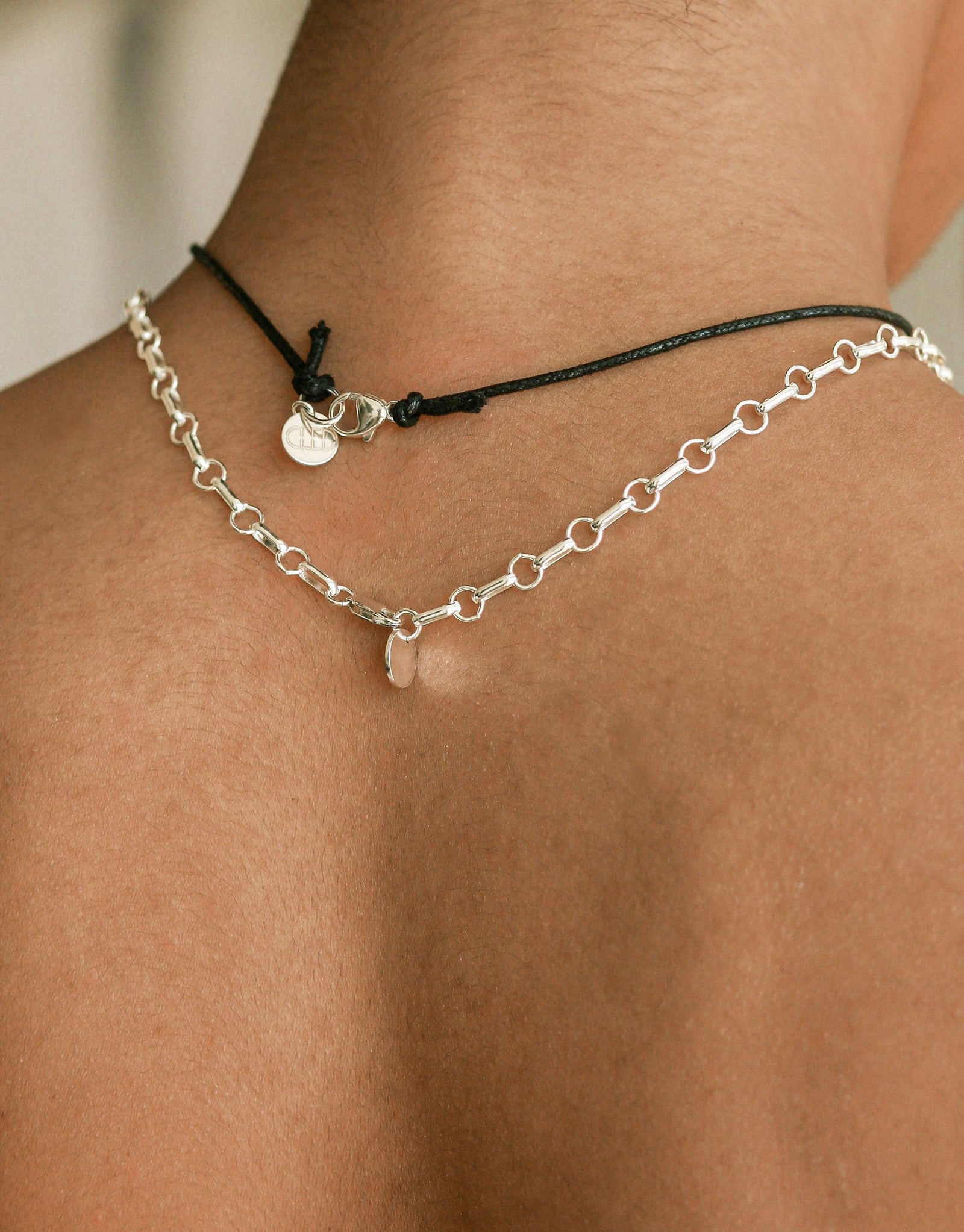Close-up of Sculptural Small Charm Necklace | B on neck, featuring delicate silver chain and black cord with small sculptural charm. Handcrafted eco-friendly jewelry showcasing upcycled glass and sustainable materials. Elegant and minimalist design by CLED.