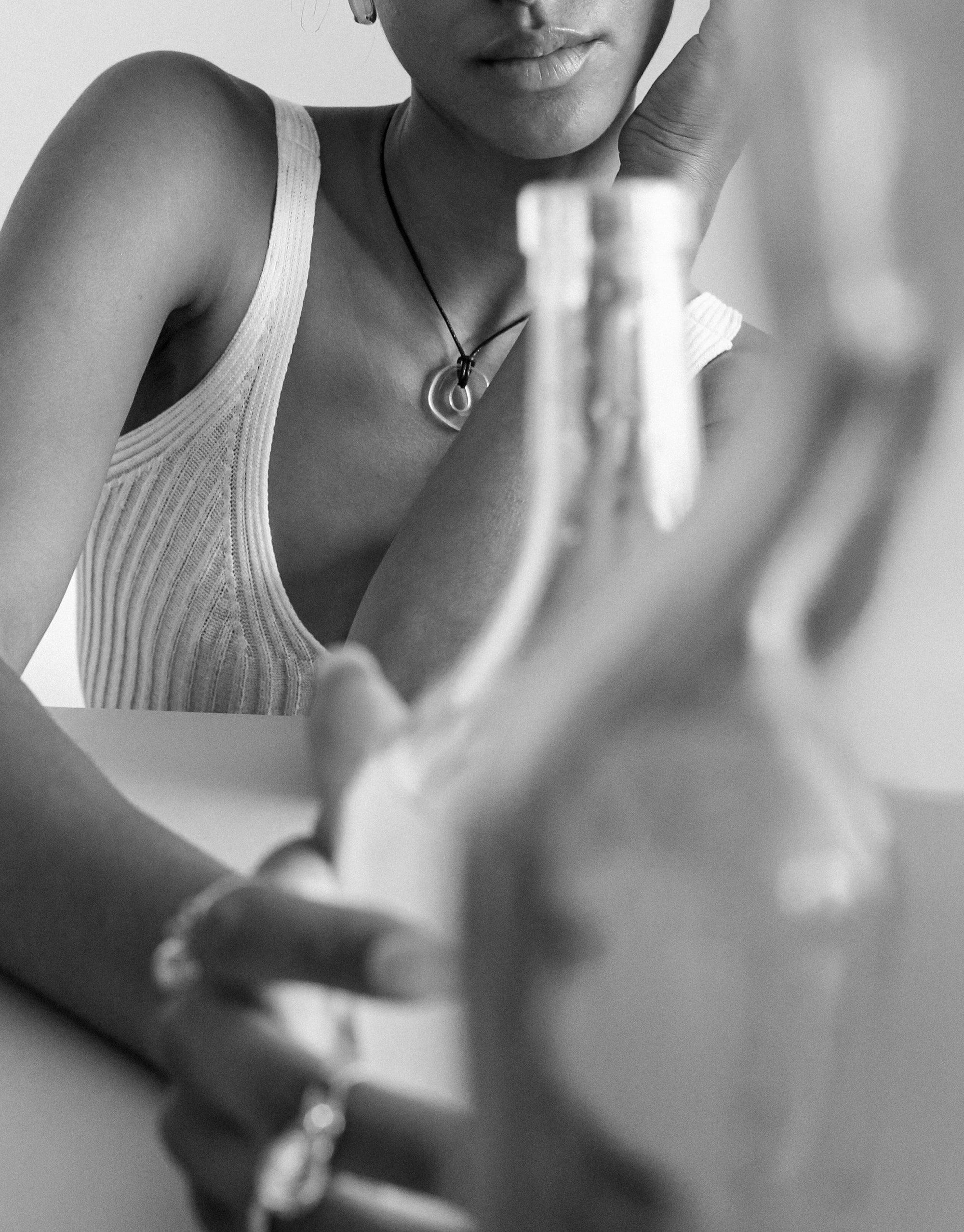 Black and white image showcasing a delicate Sculptural Small Charm Necklace on a person wearing a ribbed tank top. The necklace features a unique pendant, highlighting the handcrafted design of the Sculptural Small Charm Necklace | A by CLED.