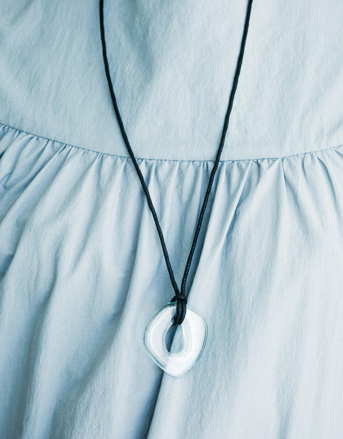 Sculptural Large Charm Necklace with upcycled glass pendant on black cord, displayed against light blue fabric. Eco-friendly, adjustable length, handmade jewelry. Sculptural Large Charm Necklace | A by CLED