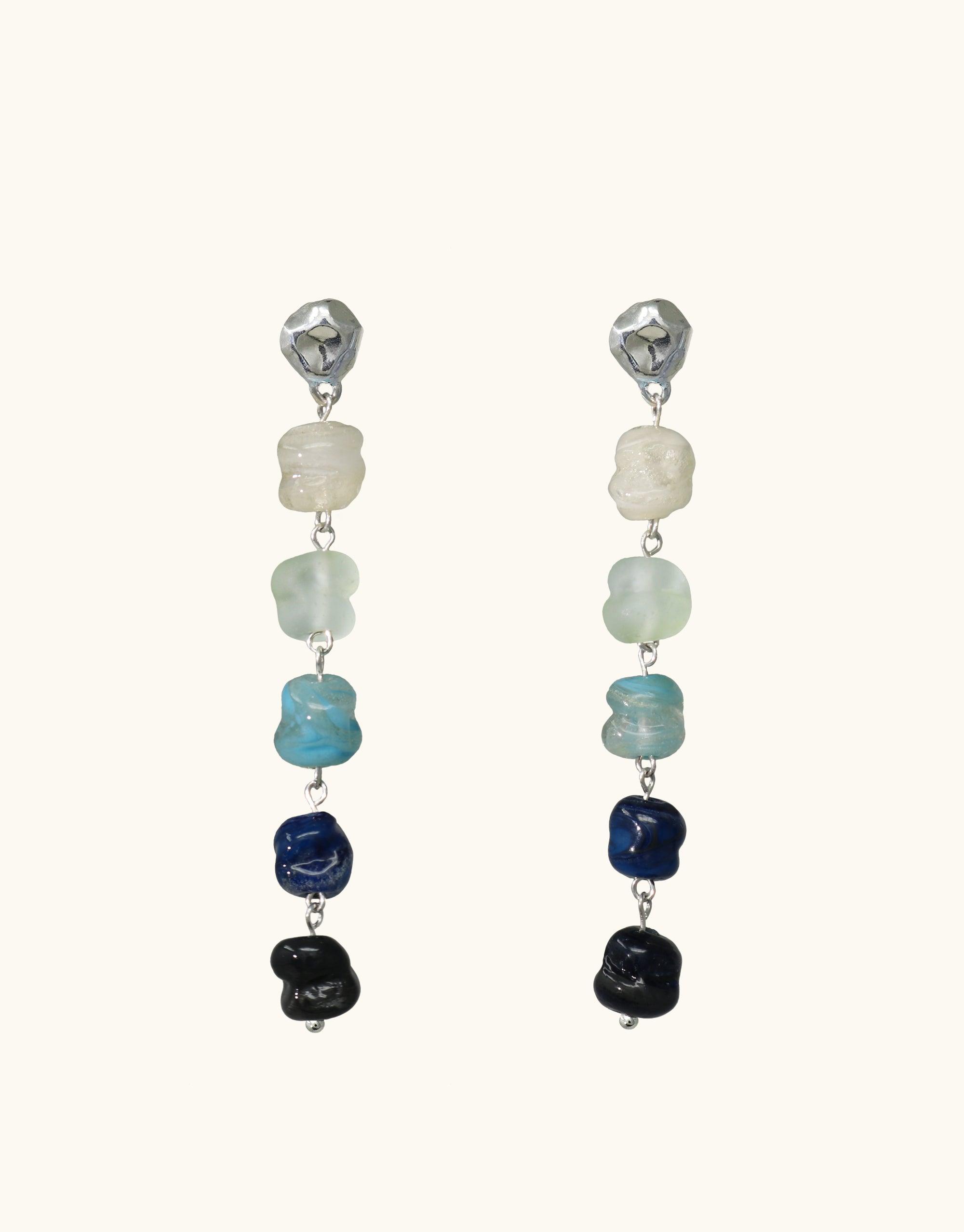 Elegant dangle earrings featuring cascading eco-friendly glass beads in shades of blue, white, and black, reminiscent of a waterfall. Handcrafted sterling silver studs complement the unique, nature-inspired design. Shades of Nature Waterfall Earrings by CLED showcase sustainable luxury and artisanal craftsmanship.