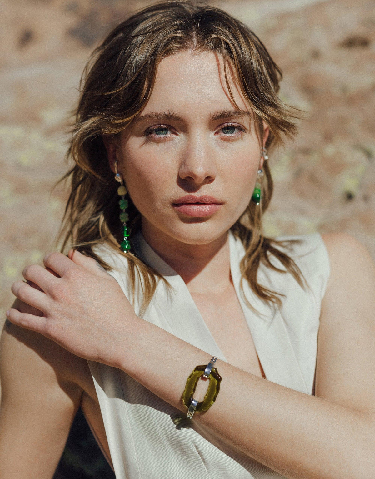 Woman wearing white top showcasing Canyon Hook Bracelet, featuring eco-glass accent in olive green. Elegant and sustainable design inspired by canyon terrain. Handcrafted jewelry piece from Terrain Collection by CLED.
