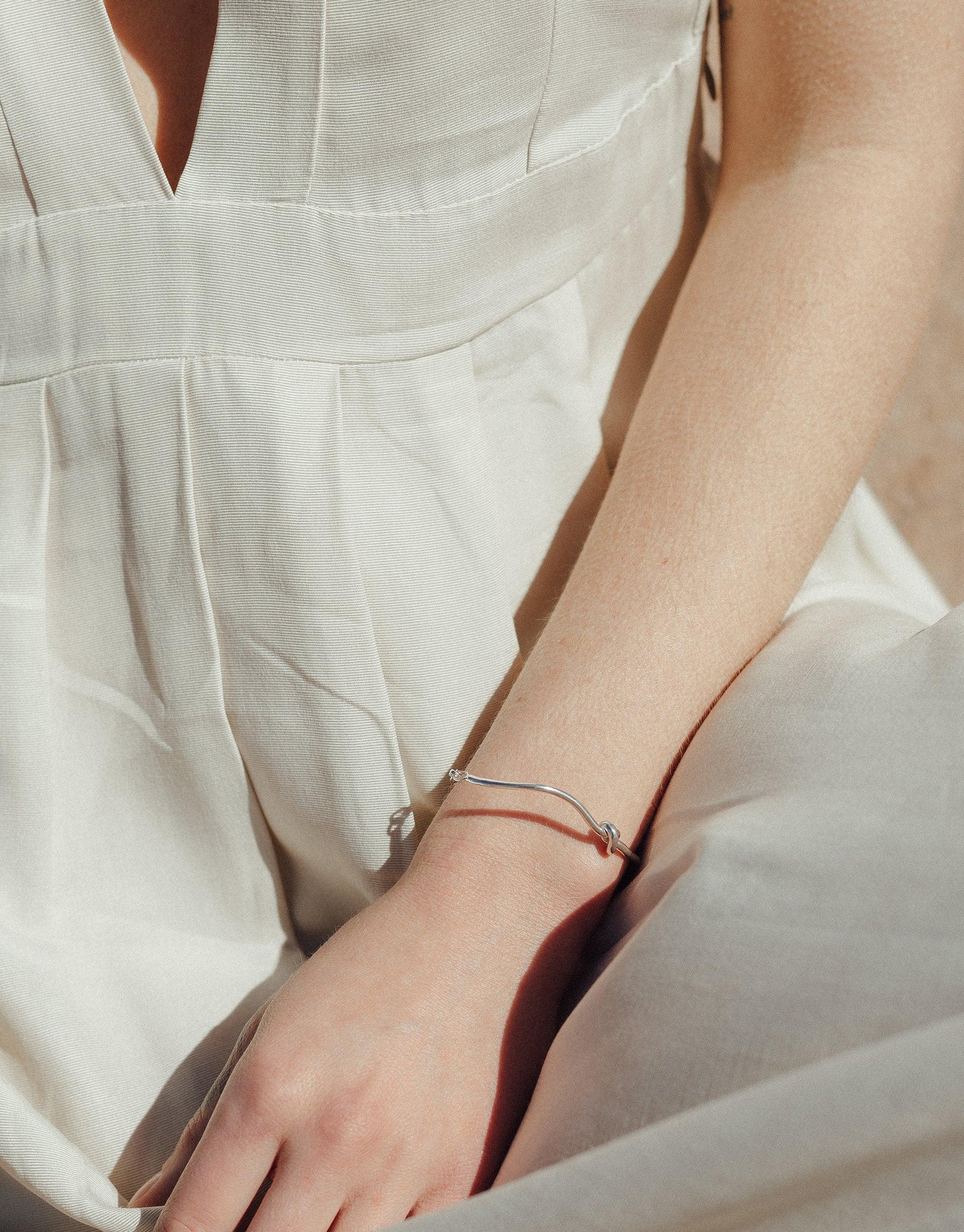 Elegant Single Rope Hook Bracelet from the Terrain Collection, showcasing a sleek metallic design inspired by canyon formations, worn on a model's wrist against a white linen background. Handcrafted in Los Angeles by CLED.