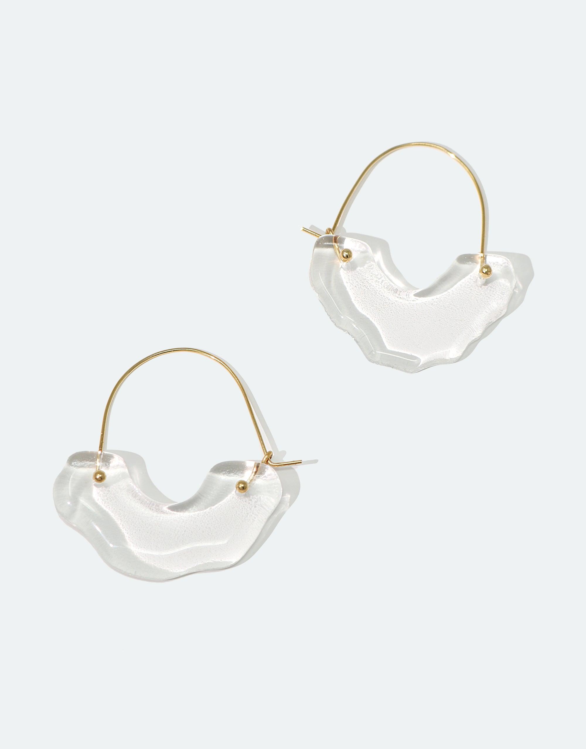 Elegant Polar Arch Hoop Earrings with translucent glass pendants inspired by icebergs, suspended from thin gold hoops. Sustainable jewelry featuring eco-friendly repurposed glass, showcasing abstract curved shapes. Handcrafted design from the Floating Glacier Collection by CLED.