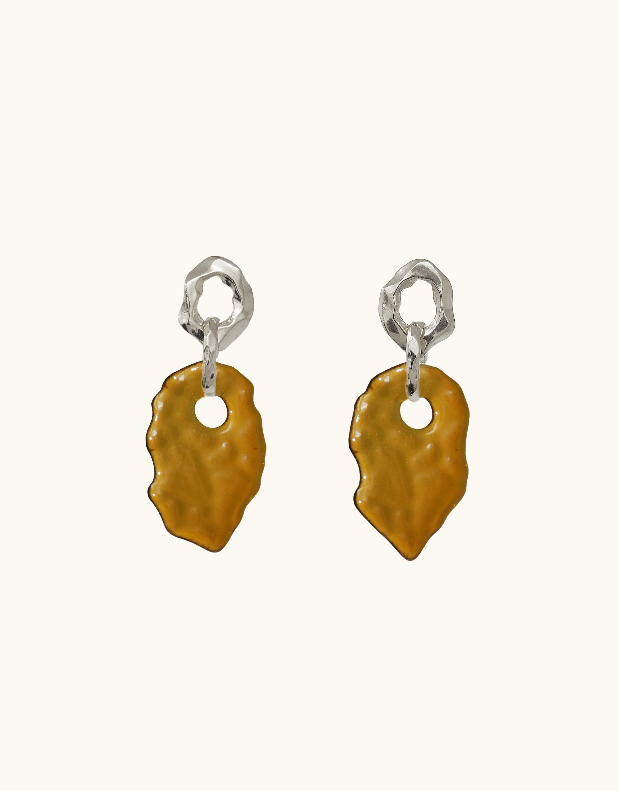 Handcrafted Canyon Earrings featuring organic silver forms and amber-colored glass pendants, inspired by layered canyon terrain. Unique eco-friendly design with repurposed glass. Elegant and sustainable jewelry piece by CLED.