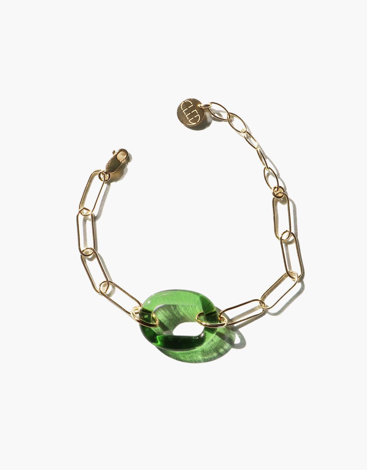The Day Loop Bracelet features a gold oval chain with a green Eco Gem stone, highlighting CLED's eco-conscious design, handcrafted from repurposed glass for a minimalistic statement piece.