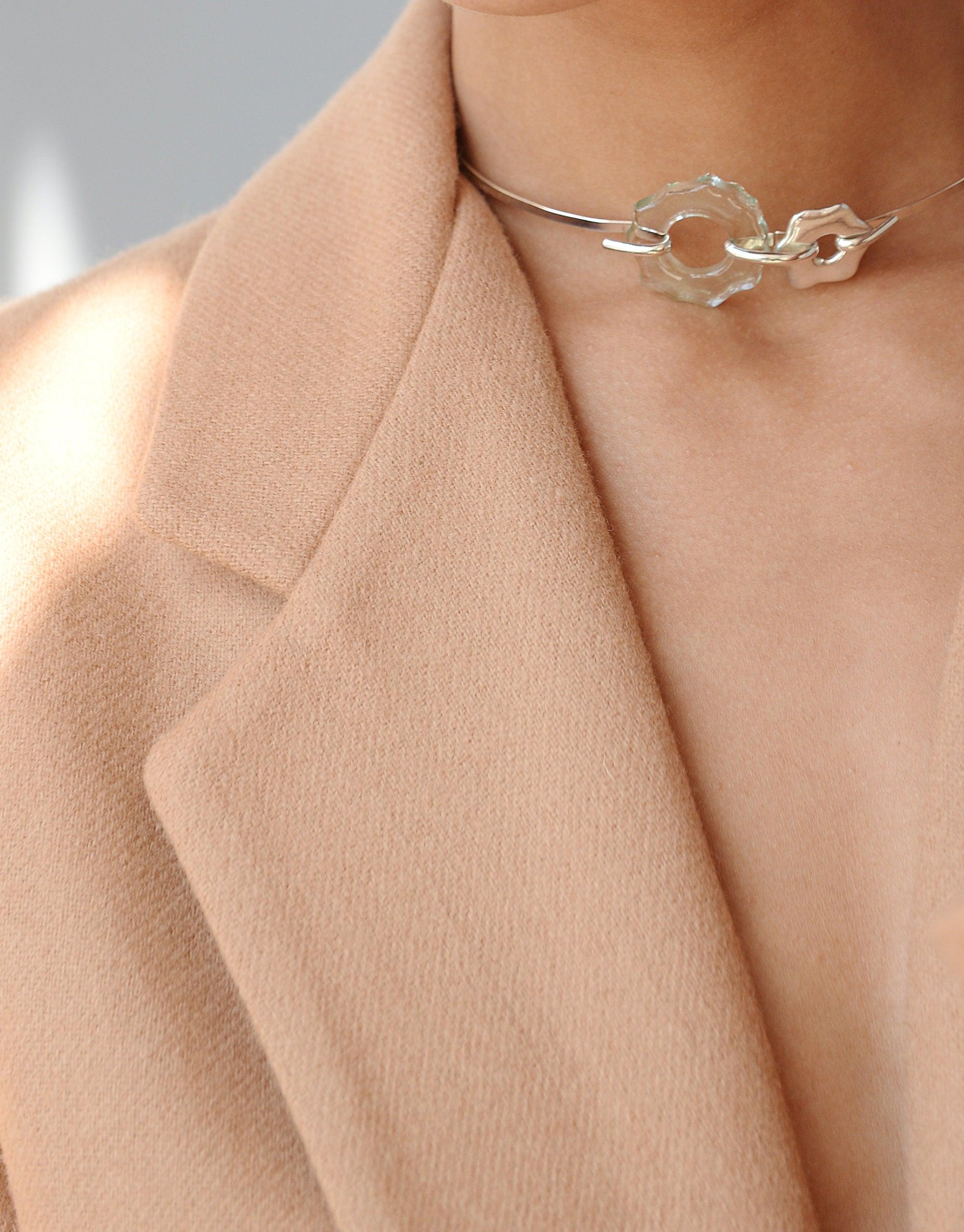 Elegant Avens Choker Necklace with eco-friendly glass drops, inspired by Arctic flowers, worn with a peach blazer. Minimalist design for versatile day-to-evening wear. Handcrafted sustainable jewelry by CLED.