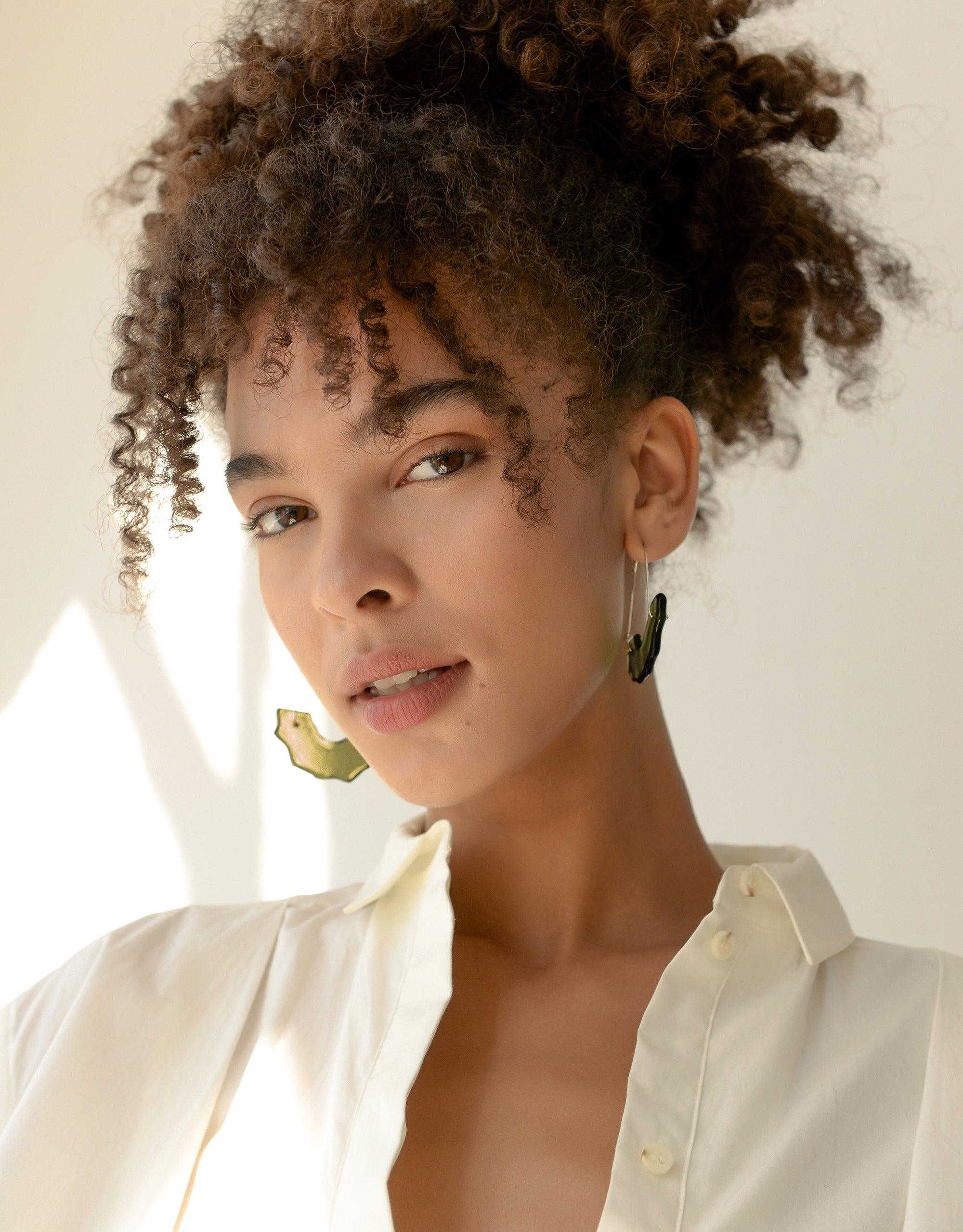 Elegant model wearing Polar Arch Hoop Earrings, showcasing abstract iceberg-inspired design. Eco-friendly jewelry made from repurposed glass, part of the Floating Glacier Collection. Sustainable fashion accessory by CLED, Polar Arch Hoop Earrings.