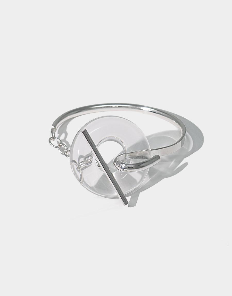 Elegant Opening Torus Toggle Bracelet featuring a transparent glass donut-shaped bead on a sleek silver cuff with toggle closure. Handcrafted sustainable jewelry piece showcasing repurposed glass and sterling silver. Timeless design by CLED.