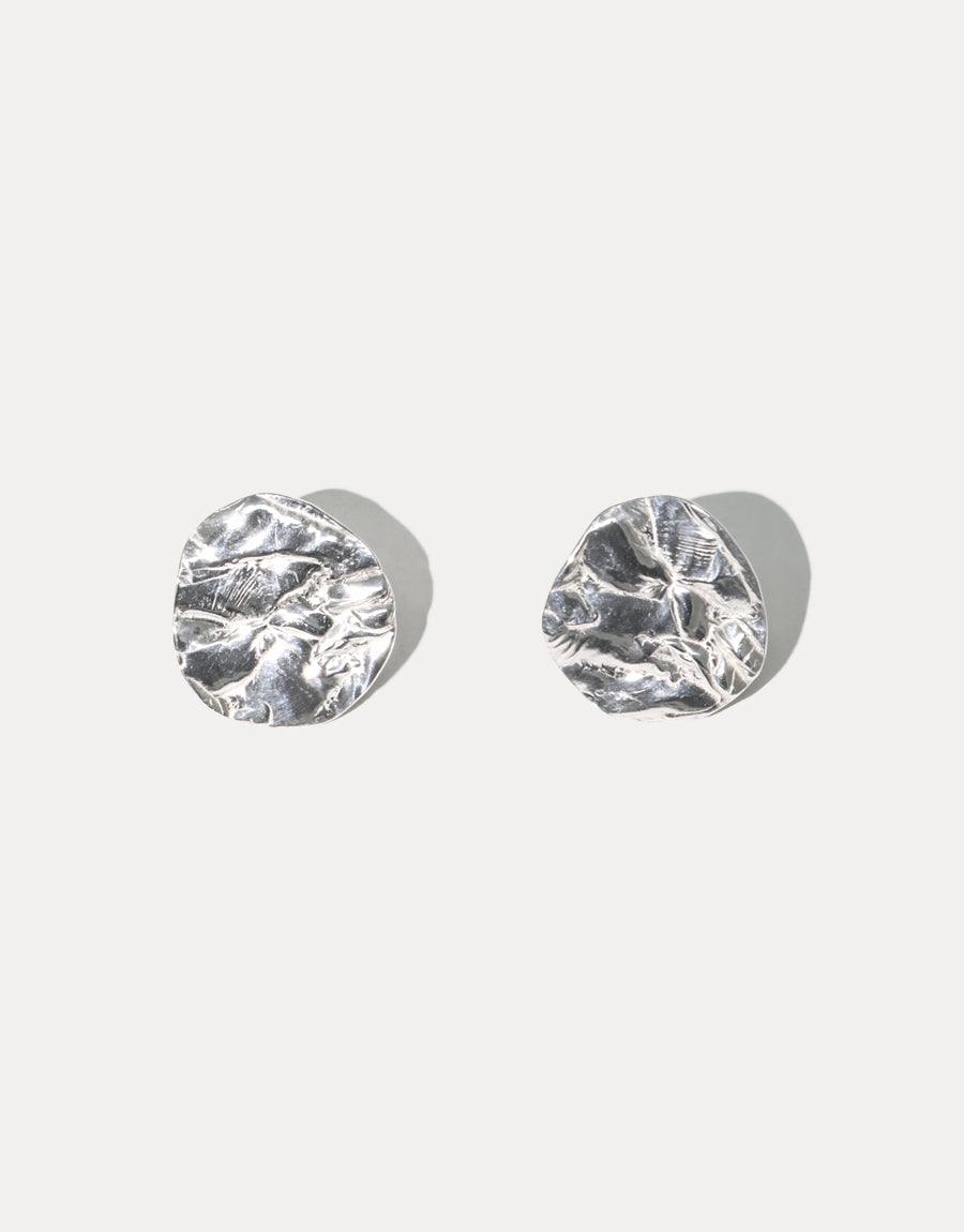 Coastline Earrings | Small Drop: Sterling silver earrings with textured, organic disc shapes inspired by coastal elements. Handcrafted with eco-friendly repurposed glass, these versatile studs feature a unique, rippled surface resembling water or sand patterns. Sustainable, artisanal jewelry by CLED.