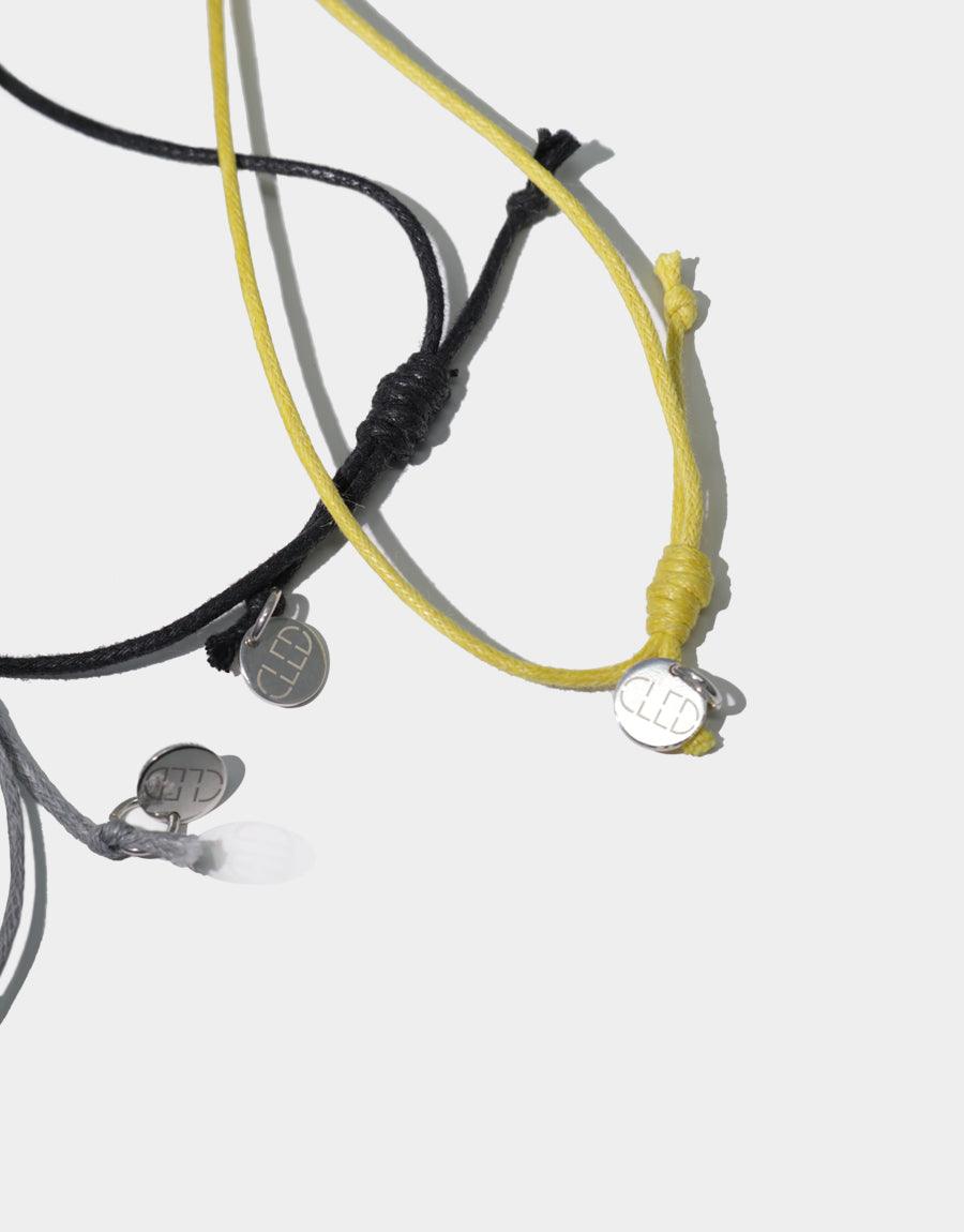 Close-up of Amorphous Long Cluster Necklace featuring adjustable cotton cords in black, yellow, and grey with silver charms. Showcases versatile design and handcrafted quality of sustainable jewelry. CLED Amorphous Long Cluster Necklace.