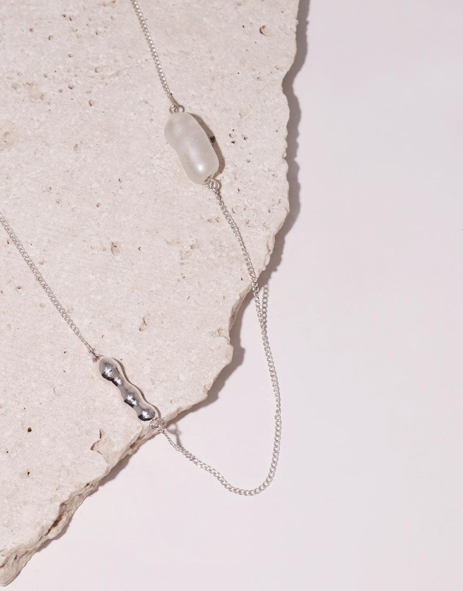 Elegant Shoreline Long Necklace featuring delicate sterling silver chain with repurposed glass water drop pendant and sustainable pearl-like Eco Gem, showcasing minimalist design and eco-friendly craftsmanship by CLED