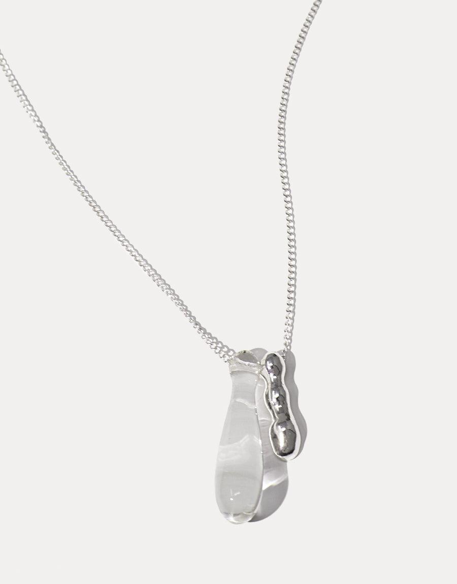 Drop Counts Necklace featuring a delicate silver chain with a transparent glass water drop pendant and wavy metal accent. Handcrafted eco-friendly jewelry symbolizing the importance of water conservation. Elegant and meaningful design by CLED.