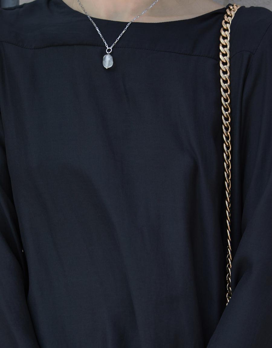 Elegant Natural Pearl Necklace featuring a delicate silver chain with a single white pearl-like pendant, worn with a black top and gold shoulder strap. Sustainable jewelry by CLED.