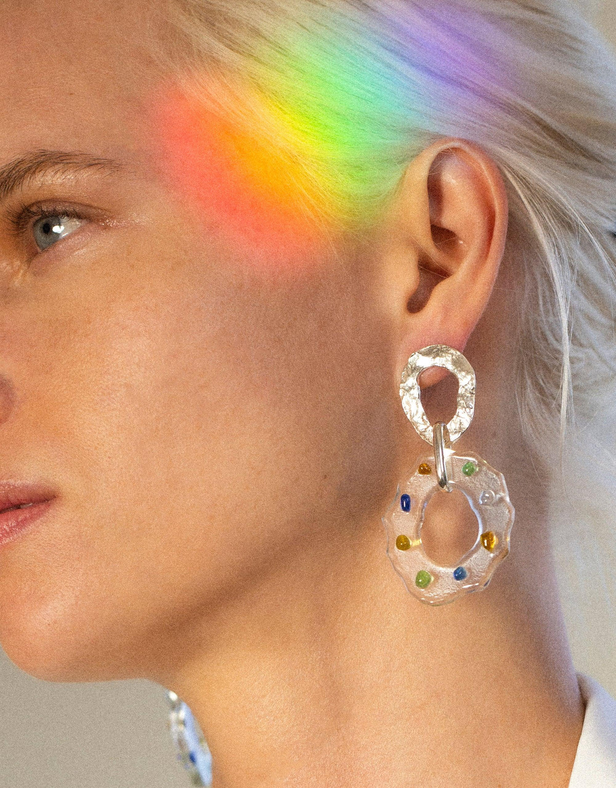 Colorful spectrum light on model wearing High Tide Earrings in Spectrum, featuring handcrafted eco gem circular design with multi-colored accents, showcasing sustainable jewelry artistry by CLED