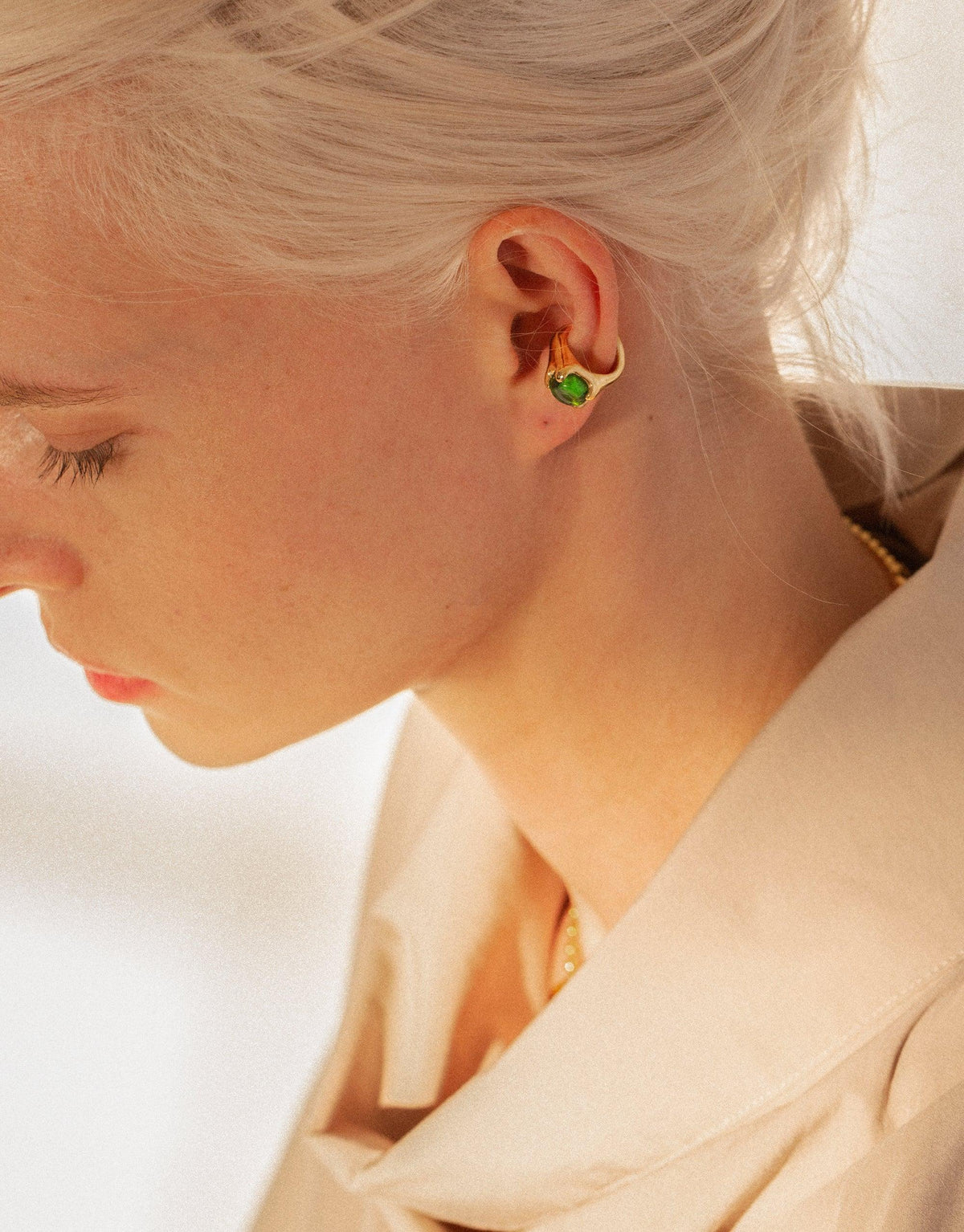 Close-up of a person wearing the Beam Ear Cuff, featuring a vibrant green eco gem repurposed from discarded glass. The ear cuff elegantly adorns the earlobe, showcasing sustainable jewelry design by CLED.