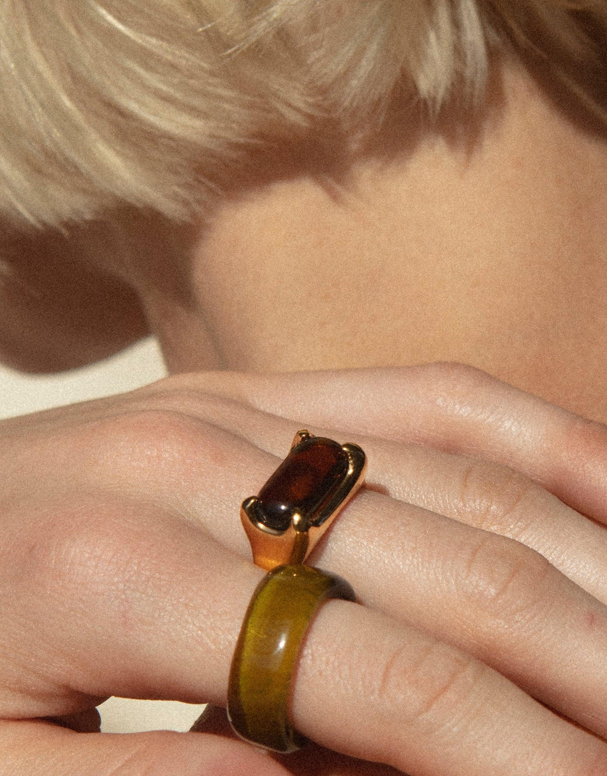 Close-up of hand wearing Prism Ring in Gold Plated, featuring a rectangular eco gem upcycled from discarded glass. The ring showcases a unique blend of gold and olive green colors, reflecting the sustainable design ethos of the Prism Ring | Gold Plated by CLED.