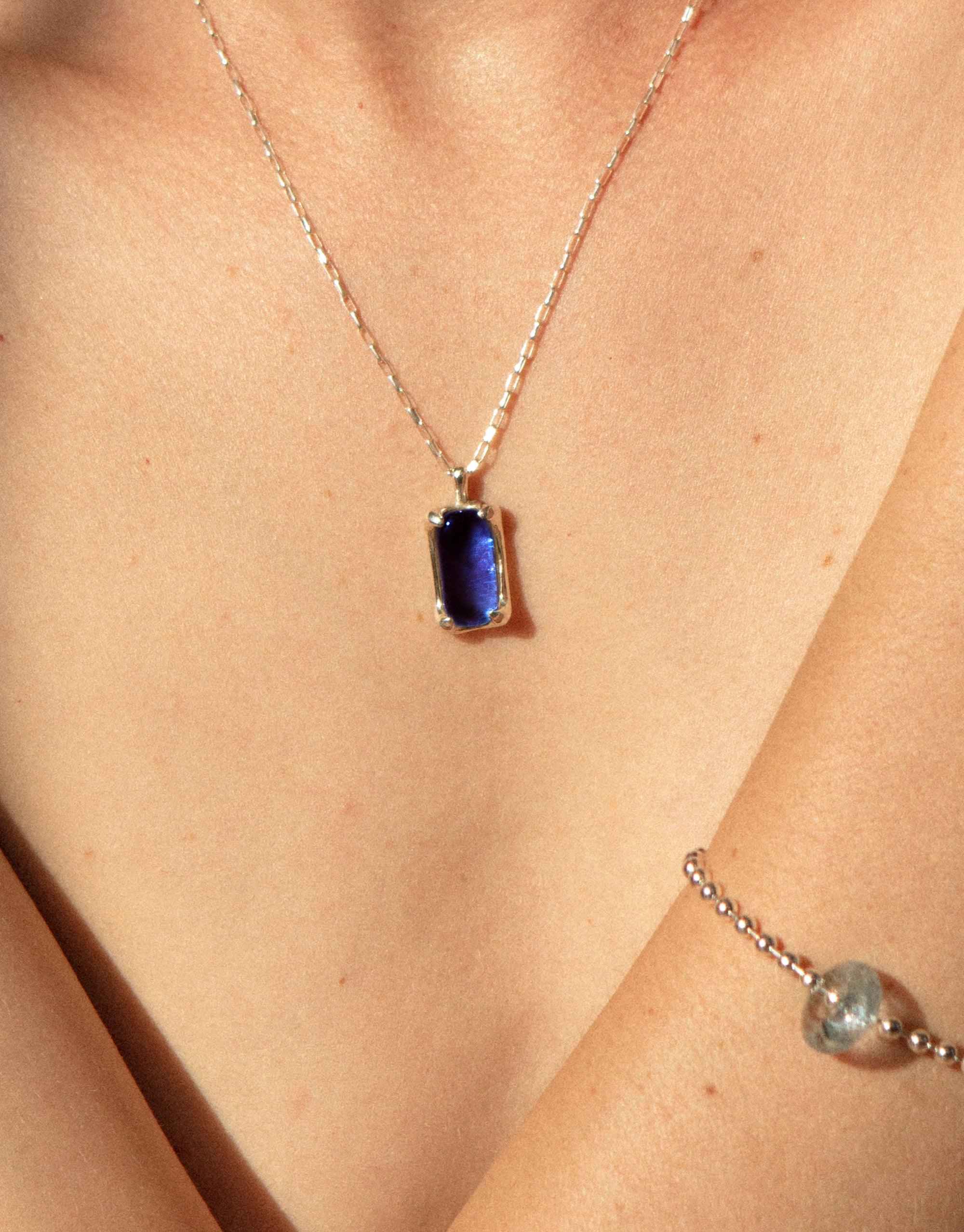 Elegant Prism Necklace featuring a vibrant blue eco gem pendant on a delicate silver chain, showcasing sustainable jewelry design. Handcrafted from upcycled glass, this necklace captures the essence of light refraction. CLED Prism Necklace.