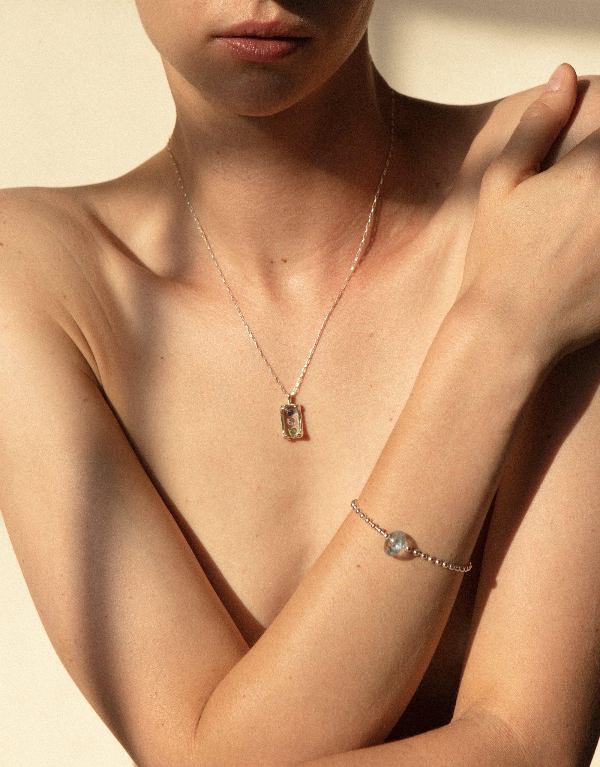 Elegant Prism Necklace showcasing delicate pendant with eco-friendly glass gem, worn by model in warm sunlight. Sustainable jewelry piece highlighting CLED's commitment to upcycling. Prism Necklace by CLED.