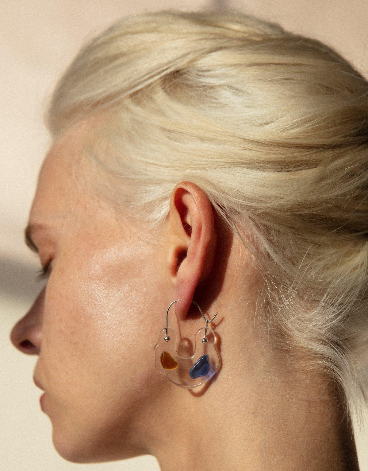 Close-up side view of an ear wearing Ray Hoop Earrings, featuring colorful eco gems in prism-like shapes. The earrings showcase sustainable jewelry design with upcycled glass, embodying the spectral colors of light. Ray Hoop Earrings by CLED.
