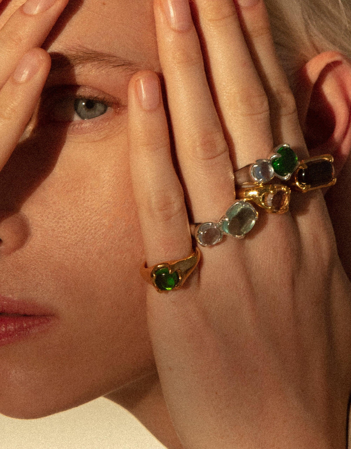 Close-up of hands with colorful gemstone rings, including the Beam Ring, showcasing eco-friendly jewelry made from upcycled glass. Vibrant prism-like colors reflect light, highlighting the unique design and craftsmanship of CLED sustainable jewelry.