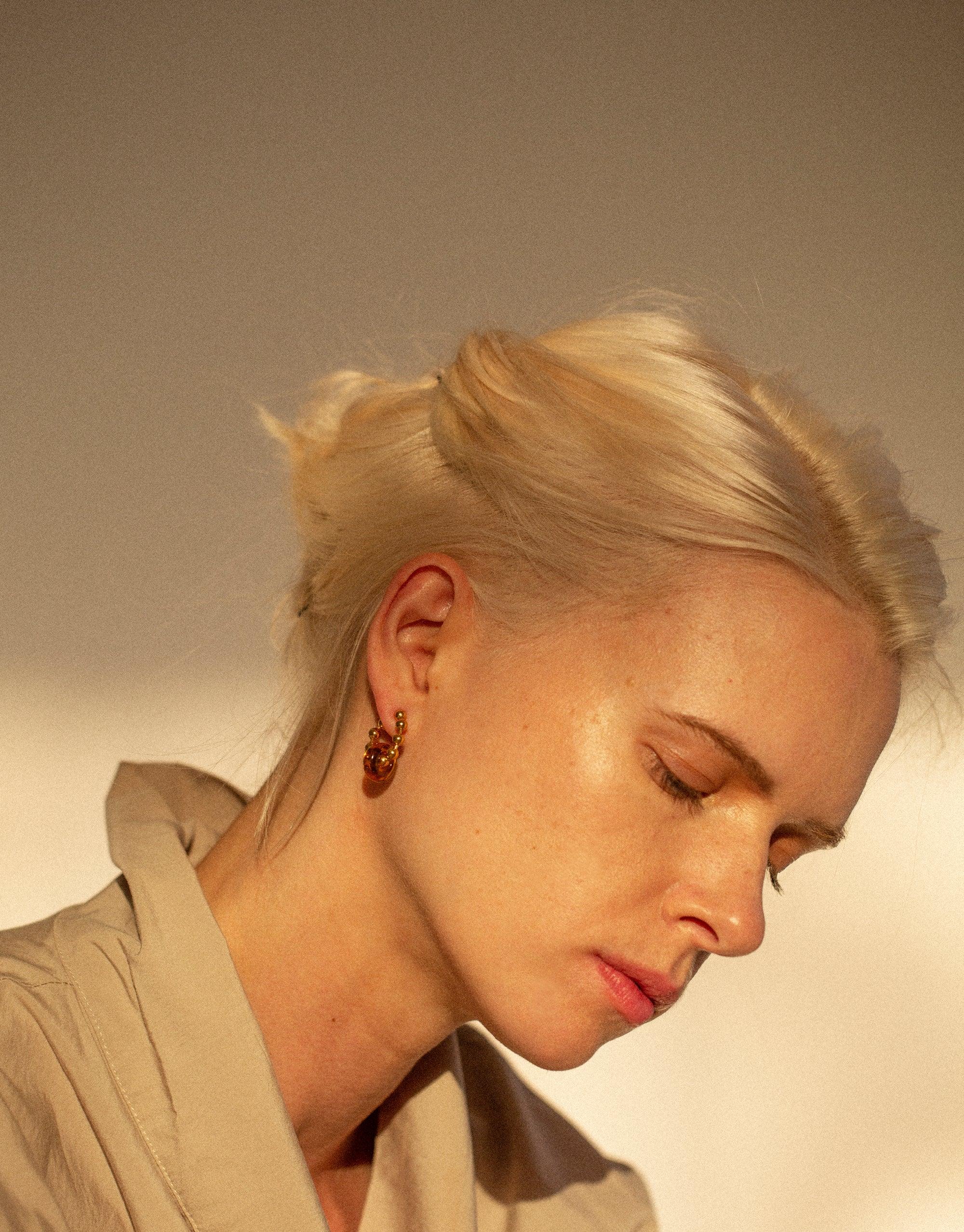 Elegant model showcasing Donut Ball Hoop Earrings, featuring eco-friendly glass upcycled into vibrant, prism-like spheres. Sustainable jewelry capturing light beautifully, handmade by CLED. Donut Ball Hoop Earrings by CLED.
